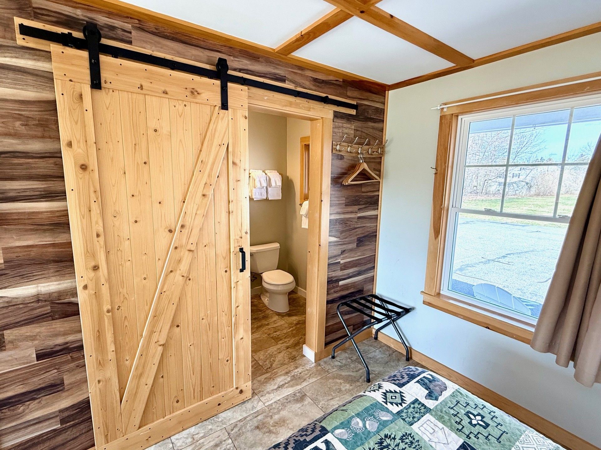 A bedroom with a sliding barn door leading to a bathroom.
