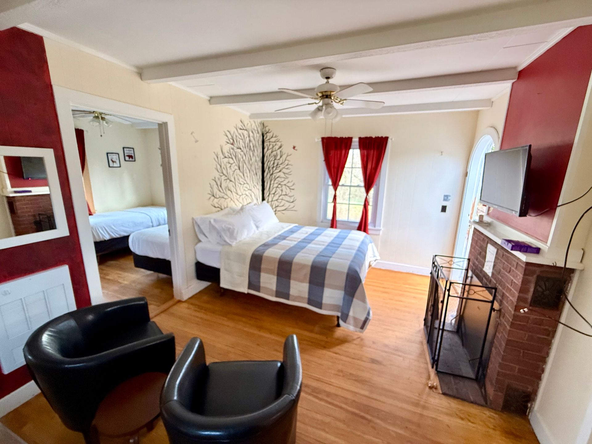 A bedroom with a bed , chairs , a fireplace and a television.