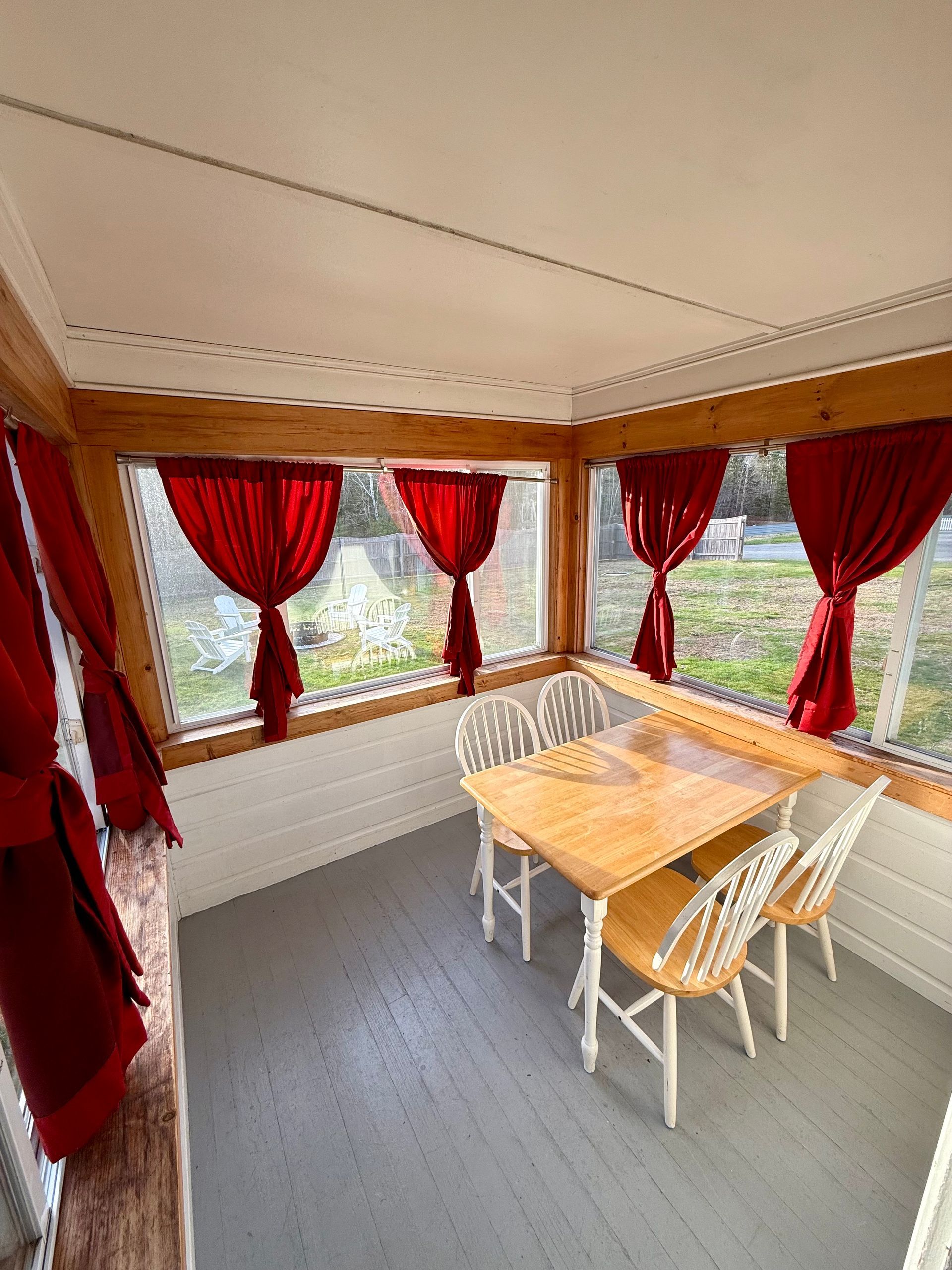 There is a table and chairs in the room with red curtains.