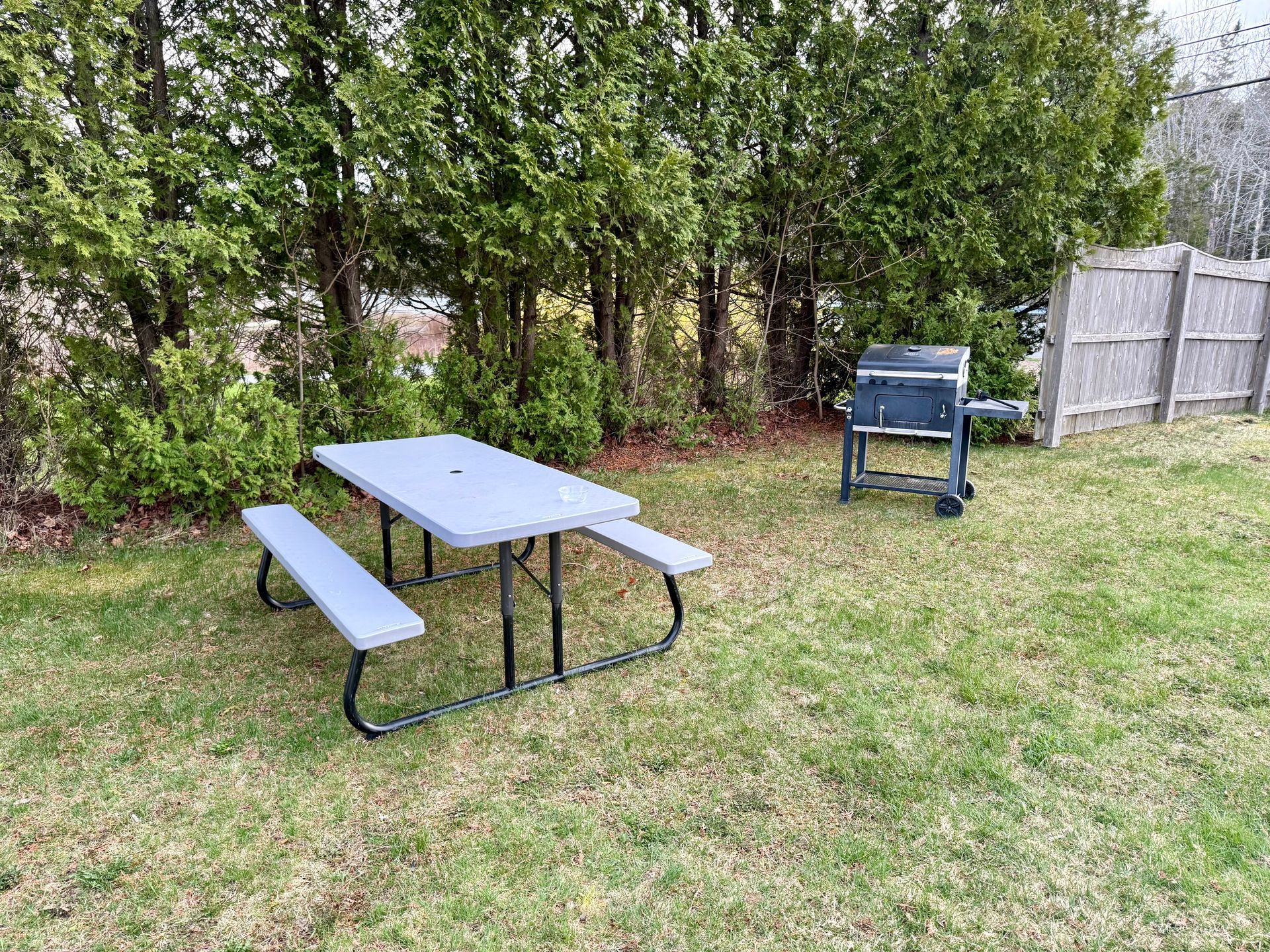 There is a picnic table and a grill in the backyard.