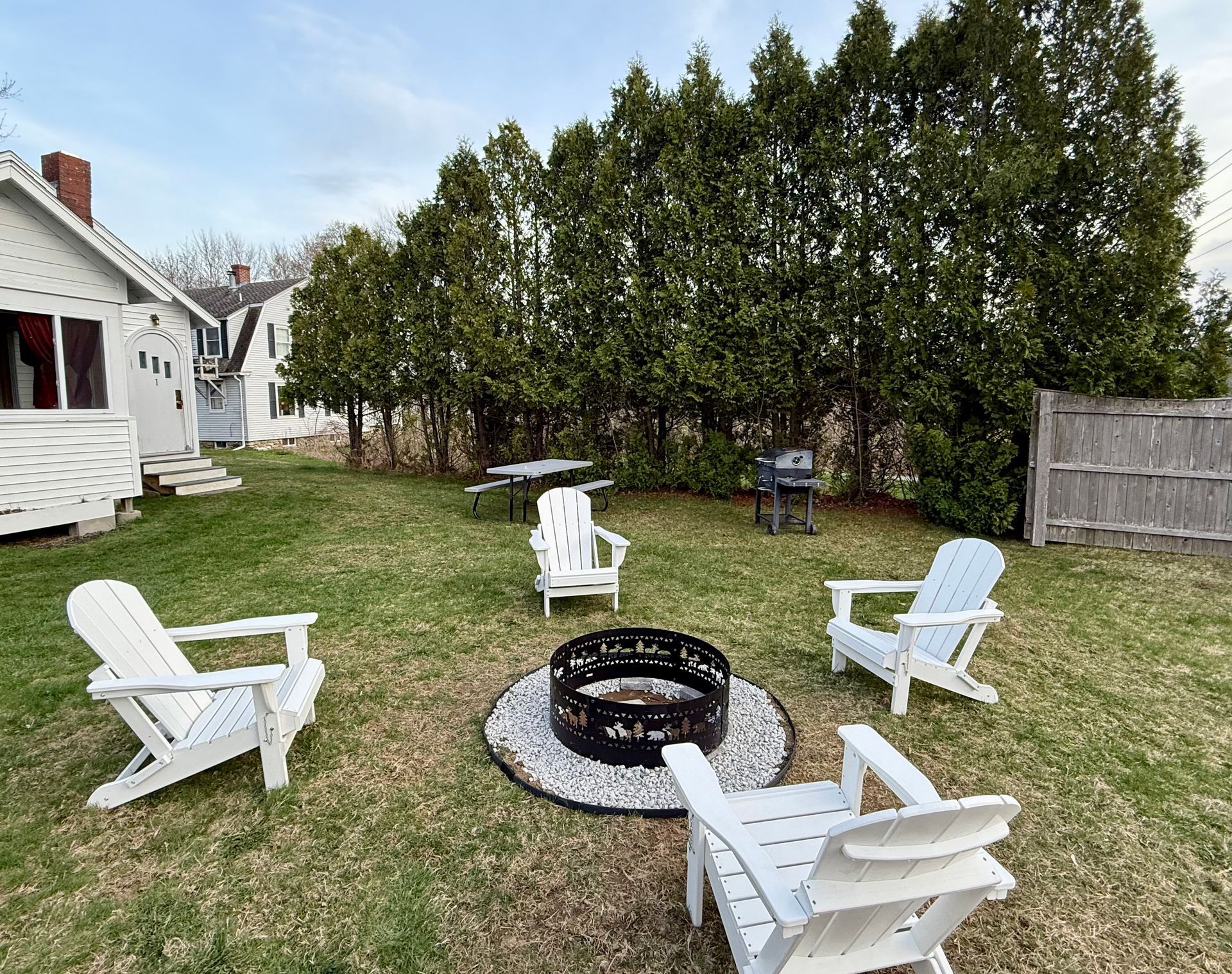 A group of chairs are sitting around a fire pit in a backyard.