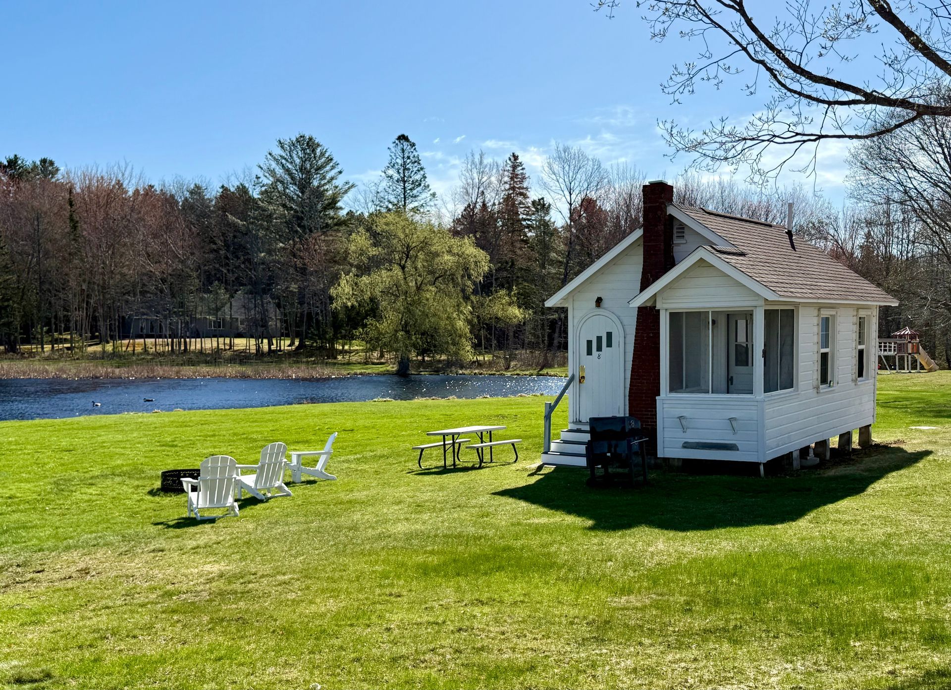 A small white house is sitting in the middle of a grassy field.