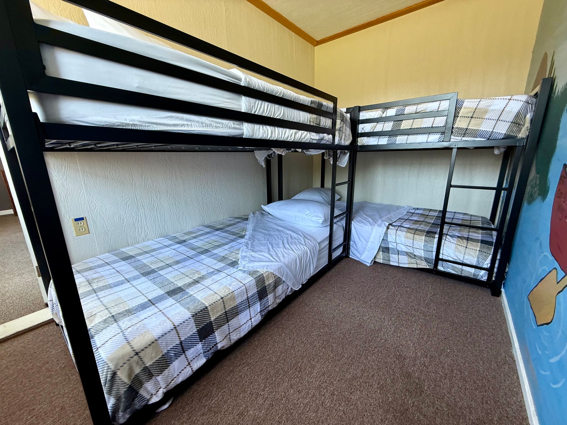 A room with three bunk beds and a painting on the wall.