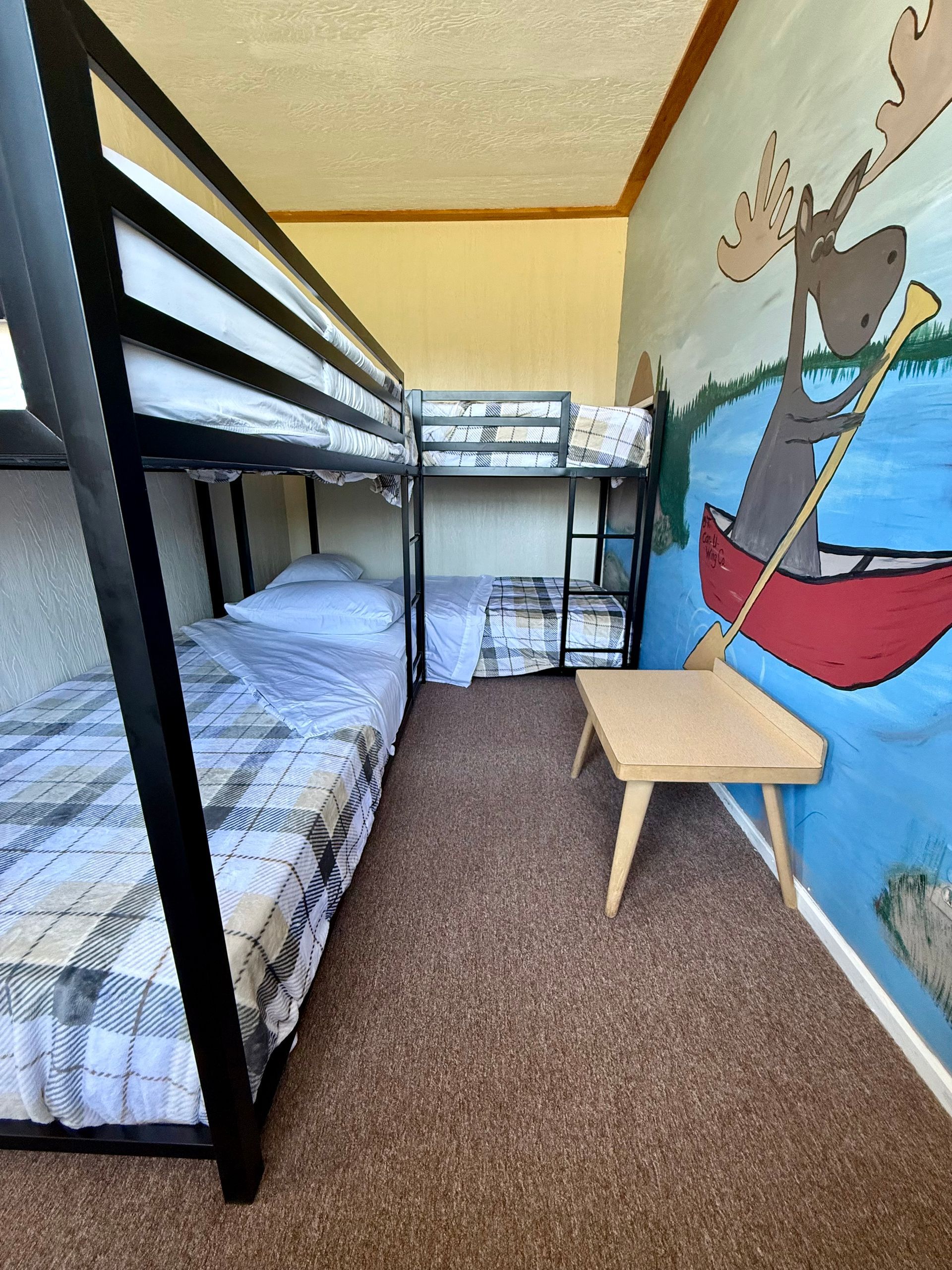 A bunk bed in a room with a moose in a canoe on the wall.