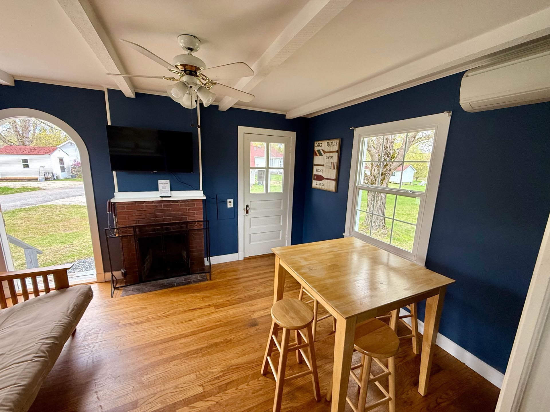 A living room with a table , stools , a fireplace and a flat screen tv.