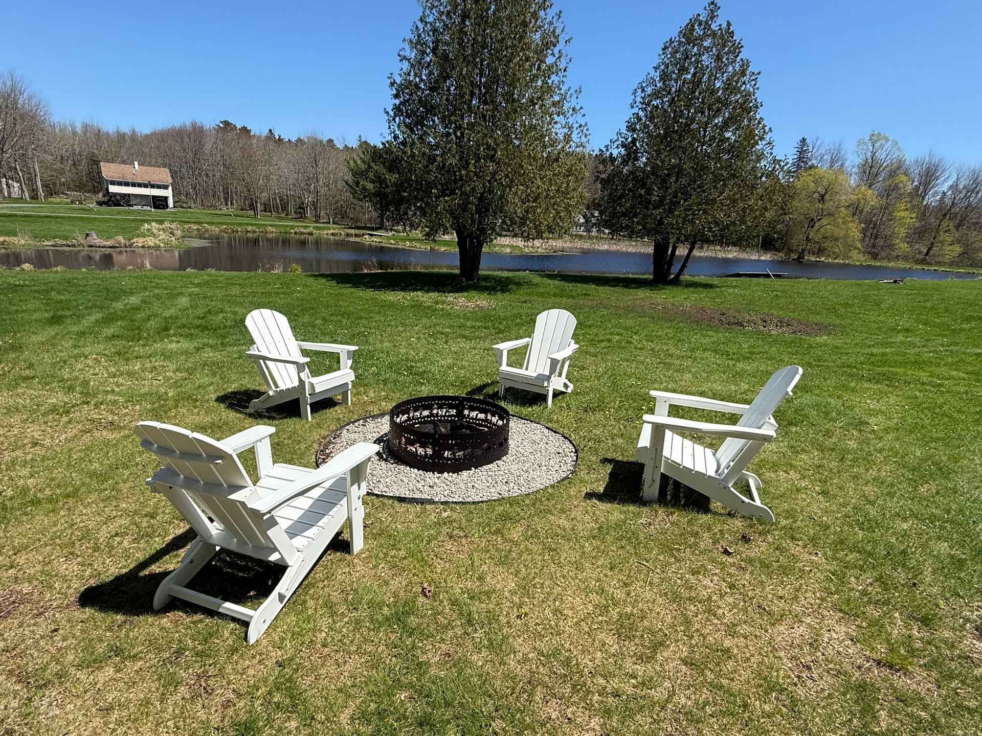 A group of chairs are sitting around a fire pit in a grassy field.