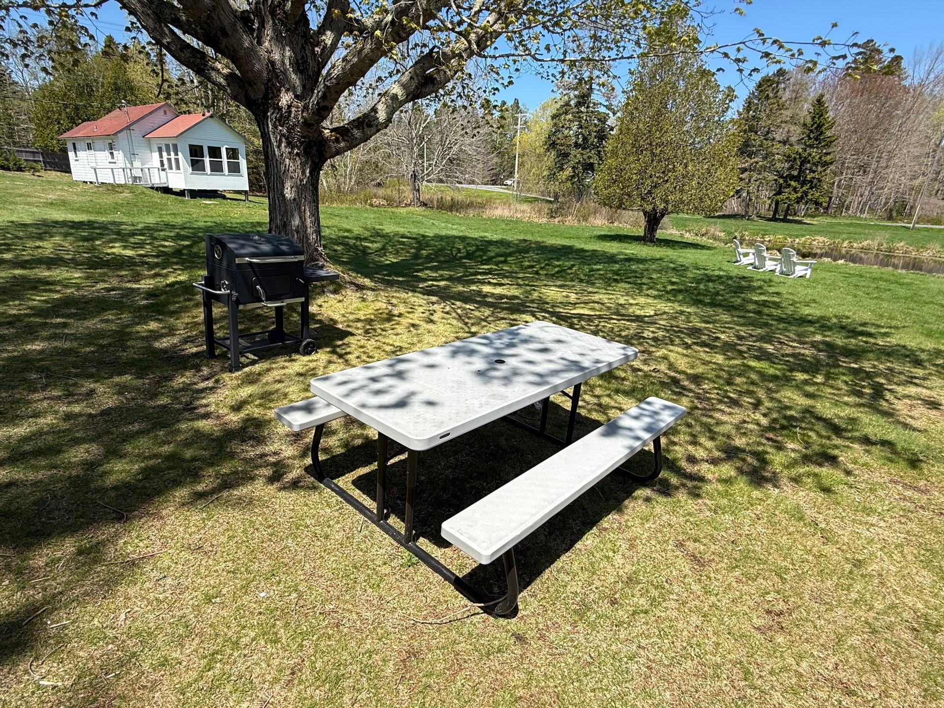 There is a picnic table and a grill in the grass.