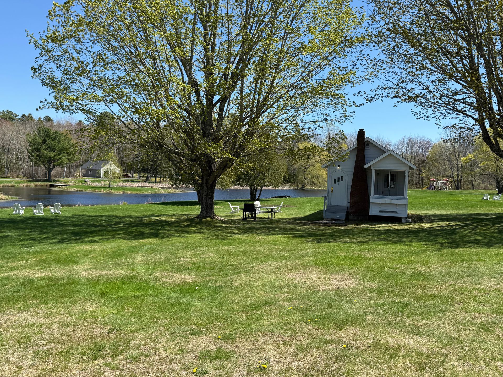 A small white house is sitting in the middle of a grassy field.
