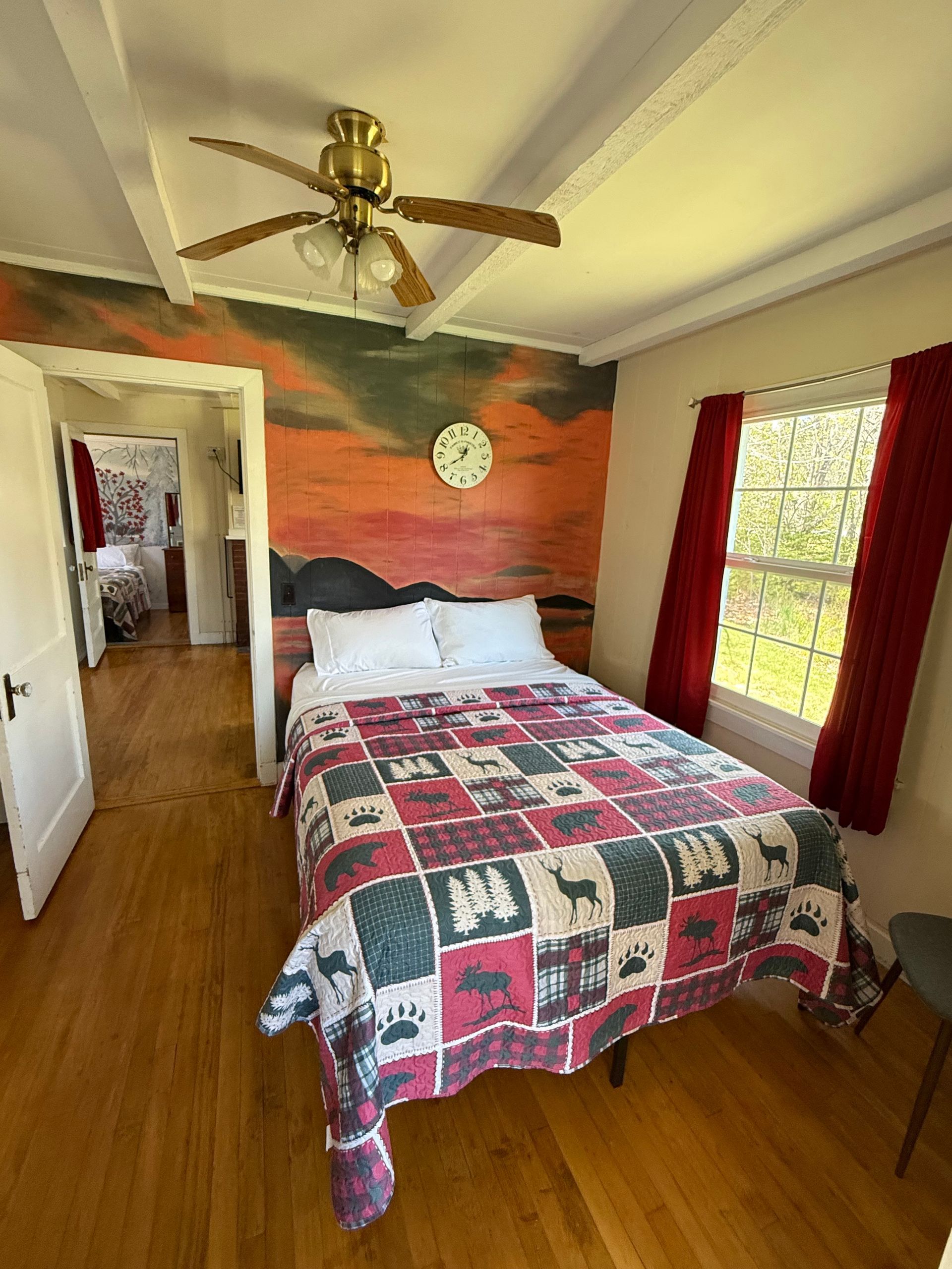 A bedroom with a bed , ceiling fan , and a painting on the wall.