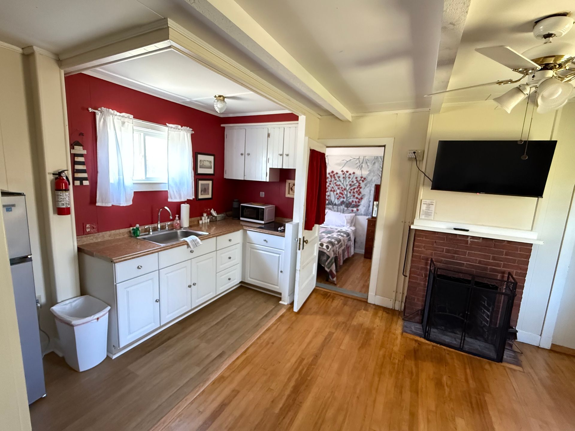 A kitchen with red walls and white cabinets and a fireplace