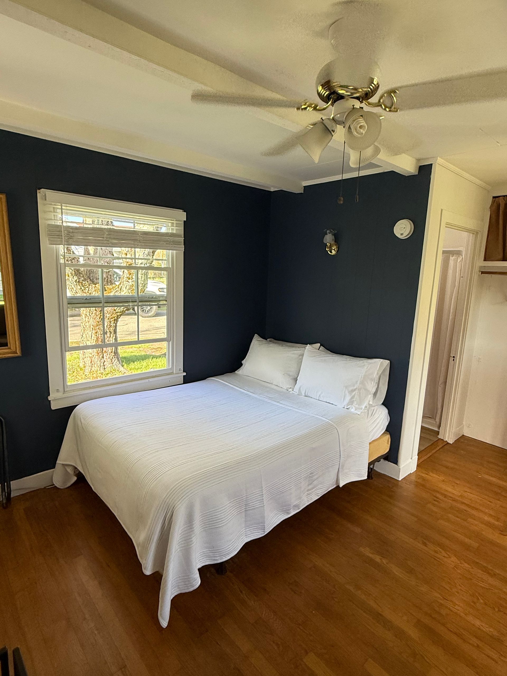 A bedroom with a bed and a ceiling fan.