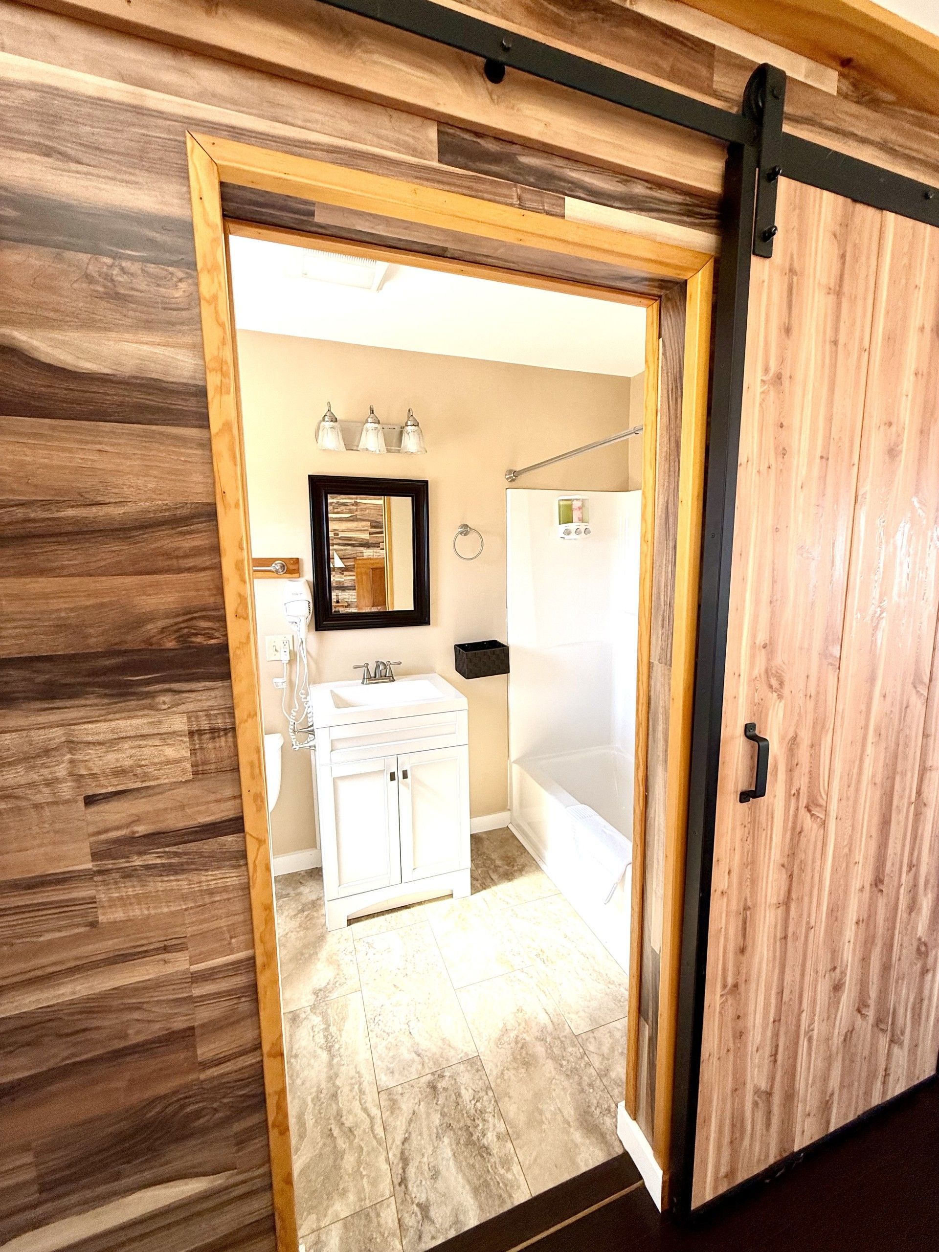 A bathroom with a sliding barn door leading to it.