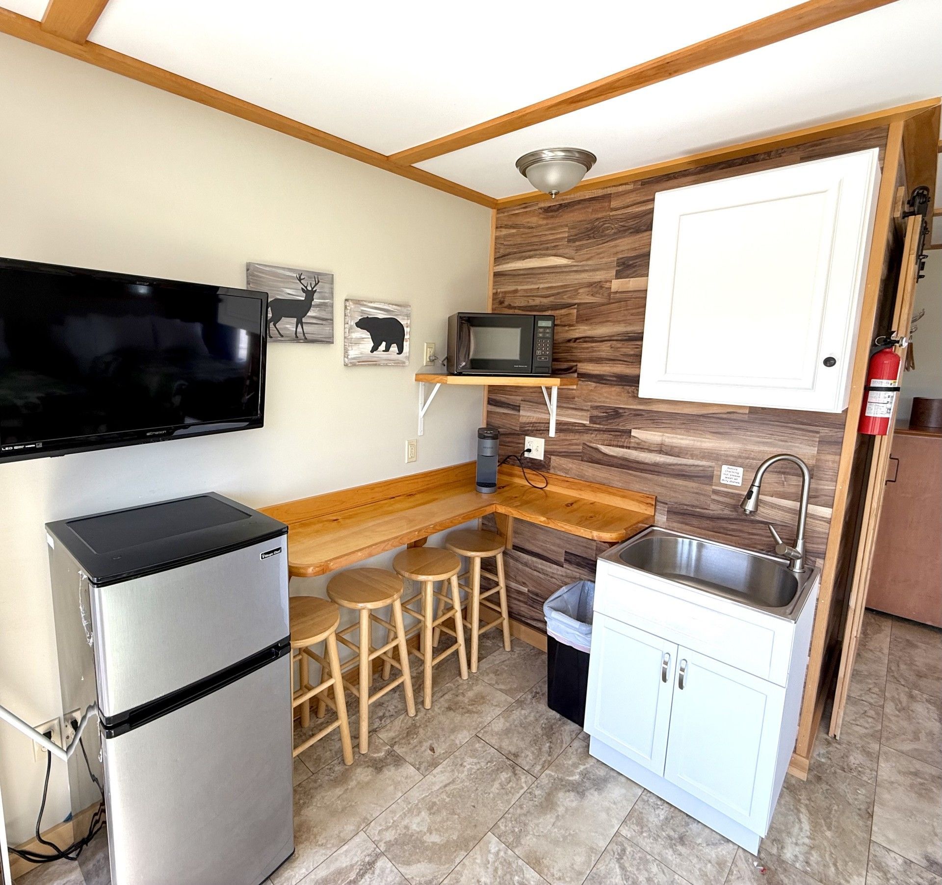 A kitchen with a refrigerator a sink and a flat screen tv