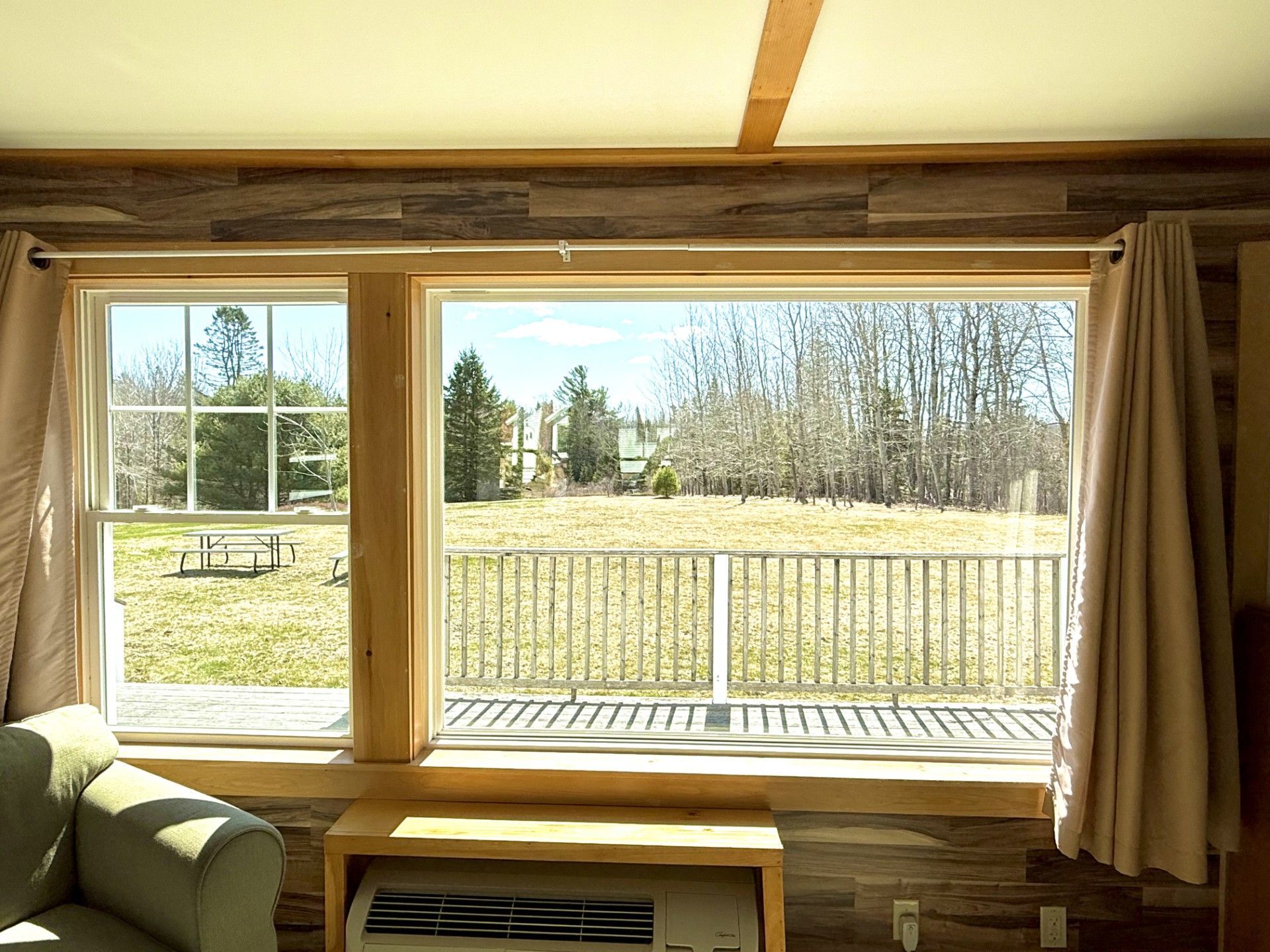 A living room with a couch and a window with a view of a field.