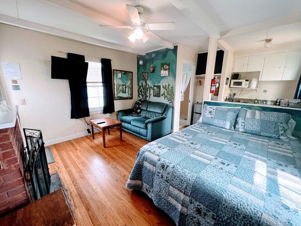 A bedroom with a bed , couch , table and fireplace.