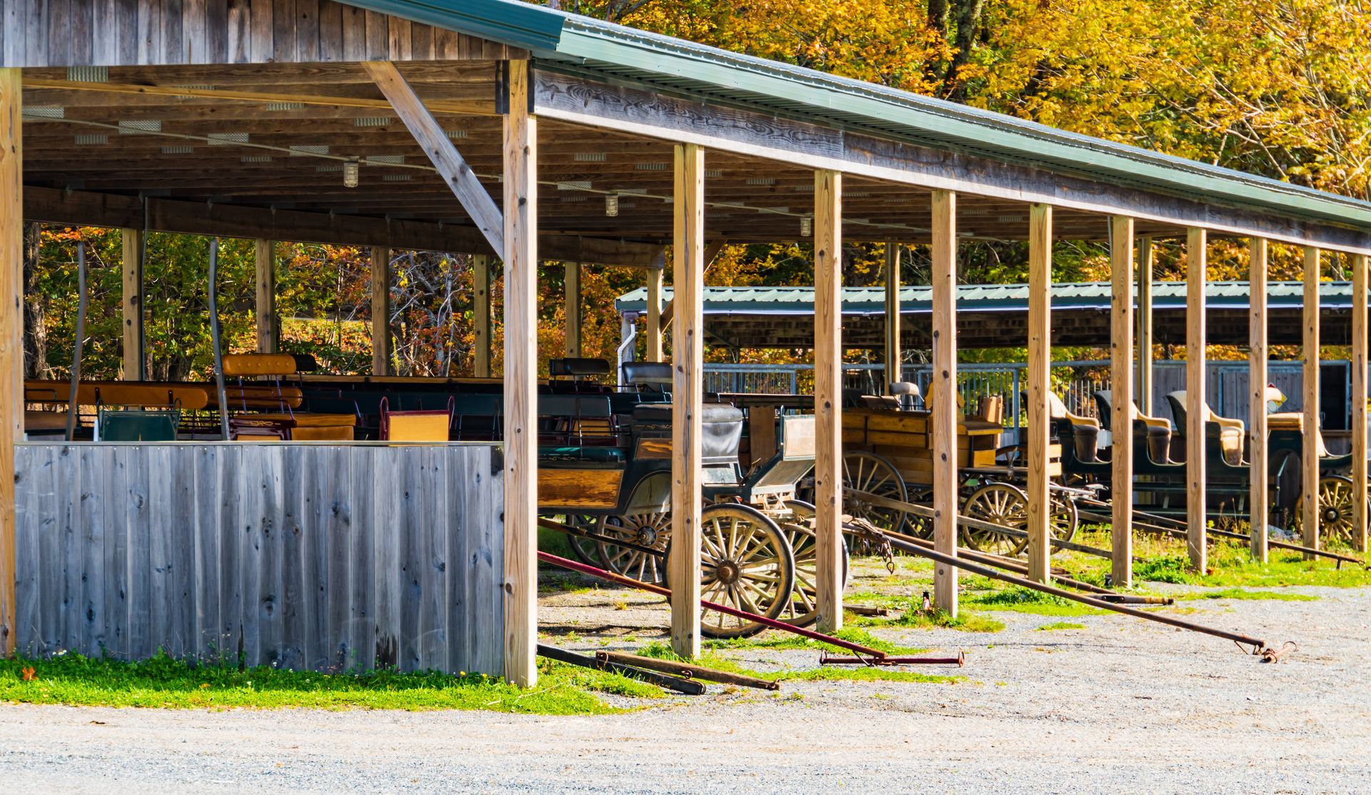 Wooden shed with carriages and equipment, likely for storage, in a rural setting.