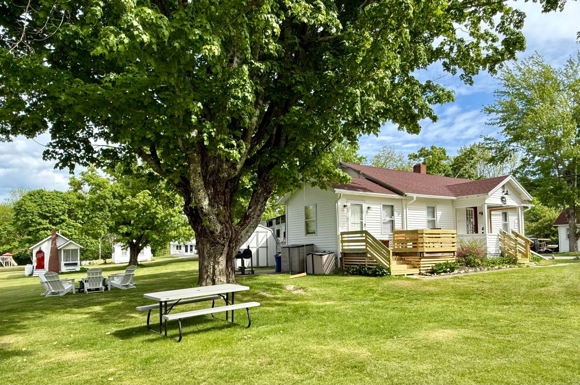 Weathered white house with a red roof; small outbuilding to the left; grassy yard.