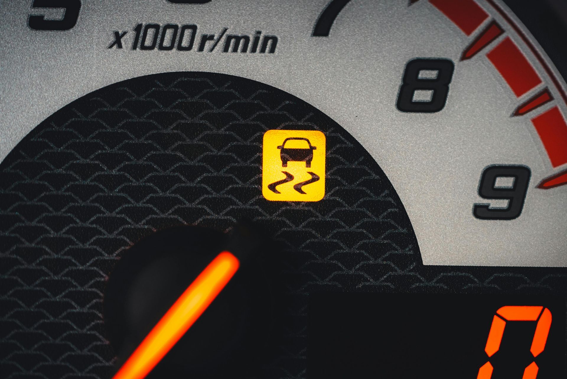 Dashboard with illuminated yellow car on a slippery road symbol, next to the RPM gauge.