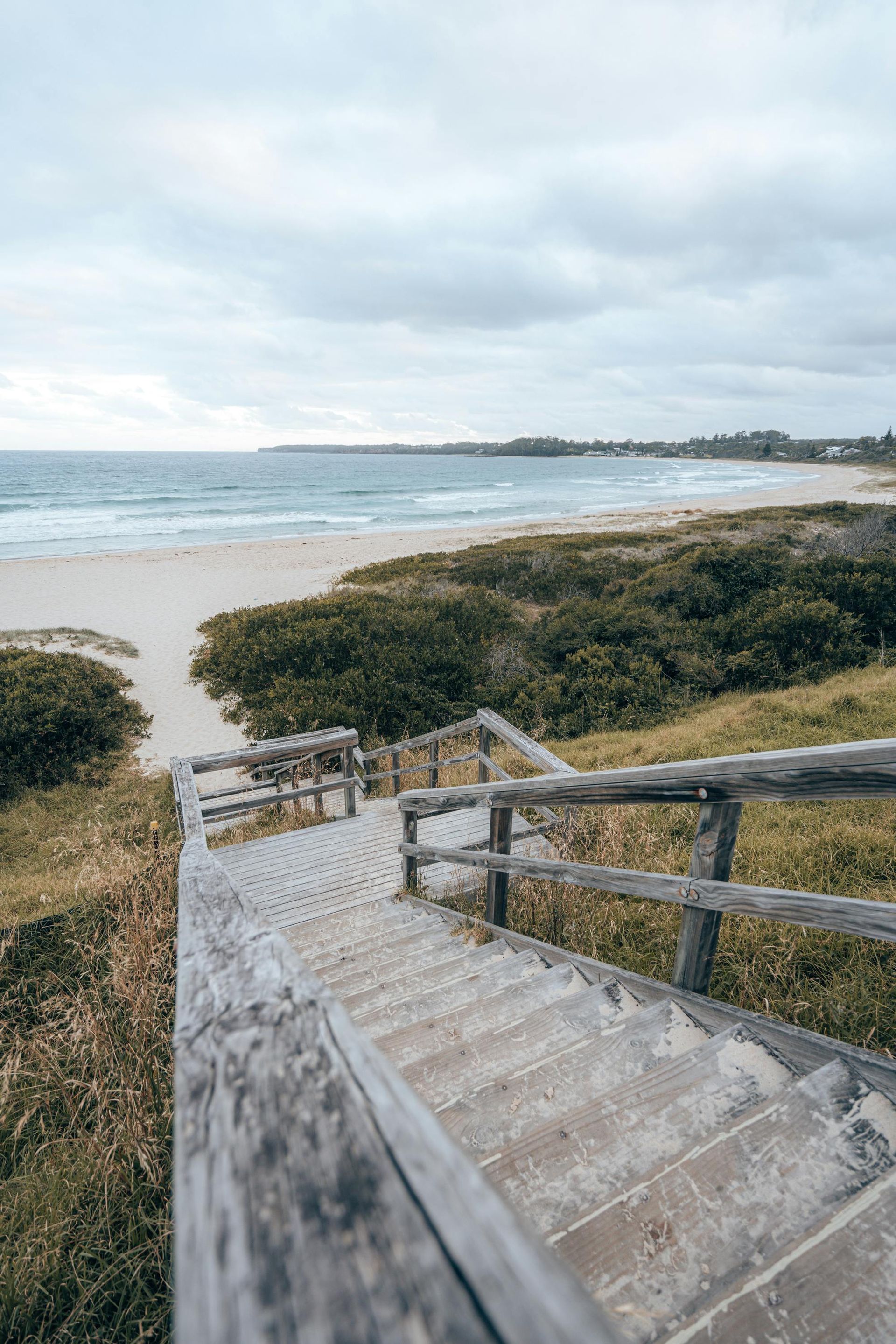 A wooden set of stairs descends to the beach
