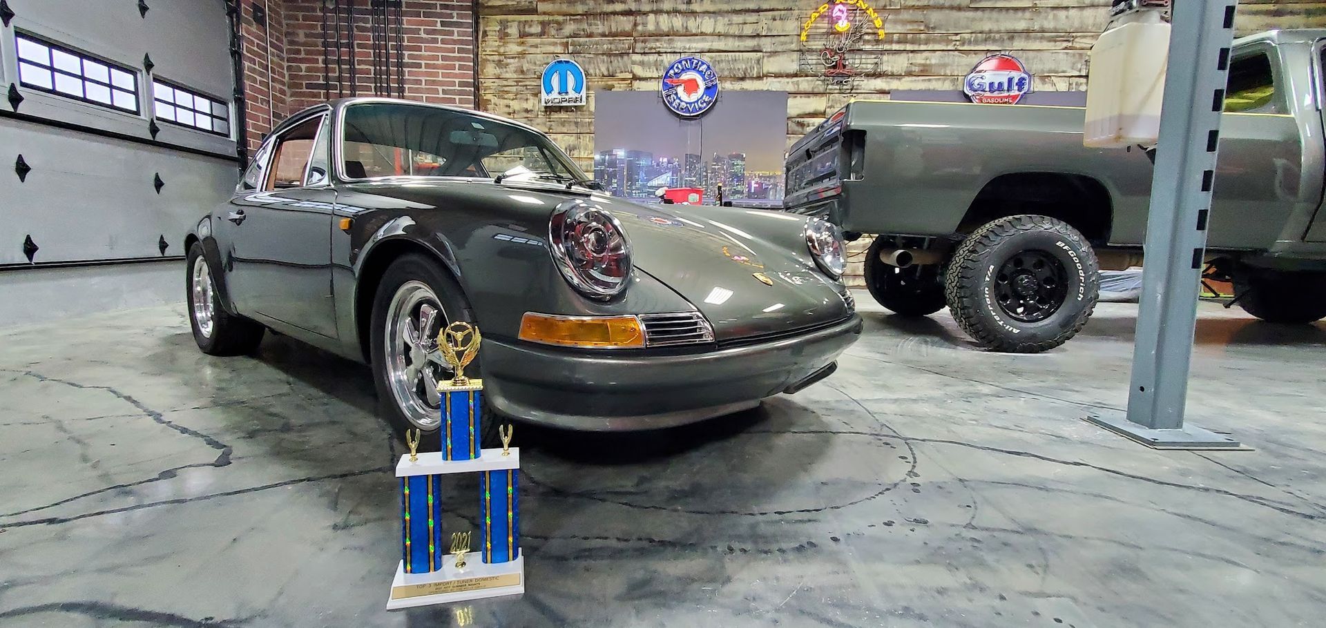 Gray Porsche convertible, trophy, truck, and car show setting.