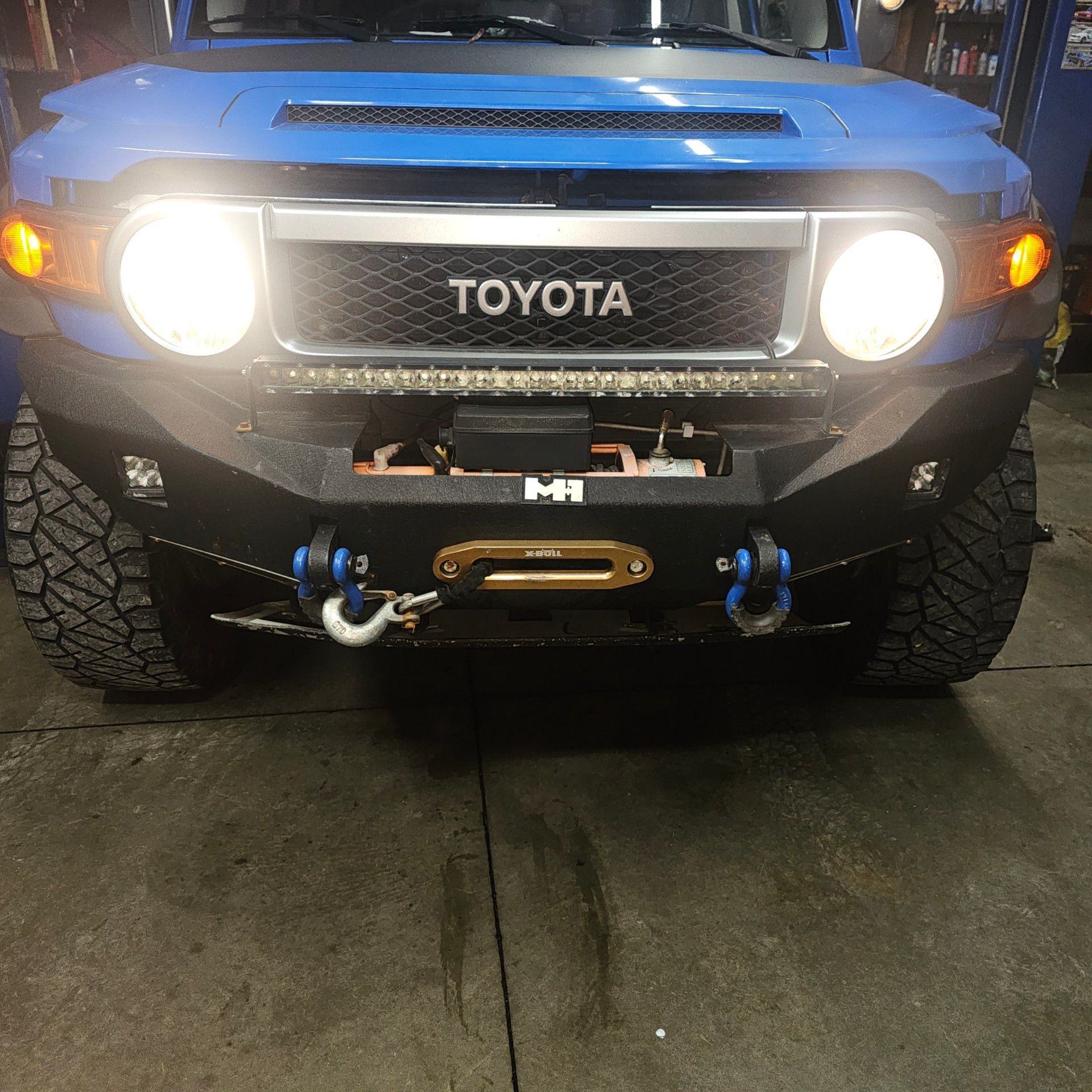 Blue Toyota FJ Cruiser with aftermarket bumper, light bar, and winch.