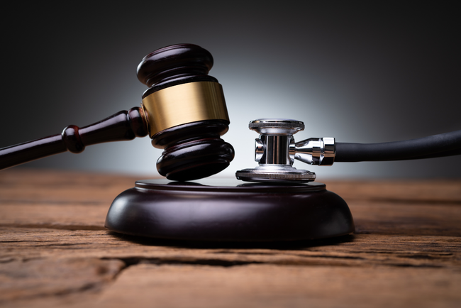 A judge 's gavel and stethoscope are on a wooden table.