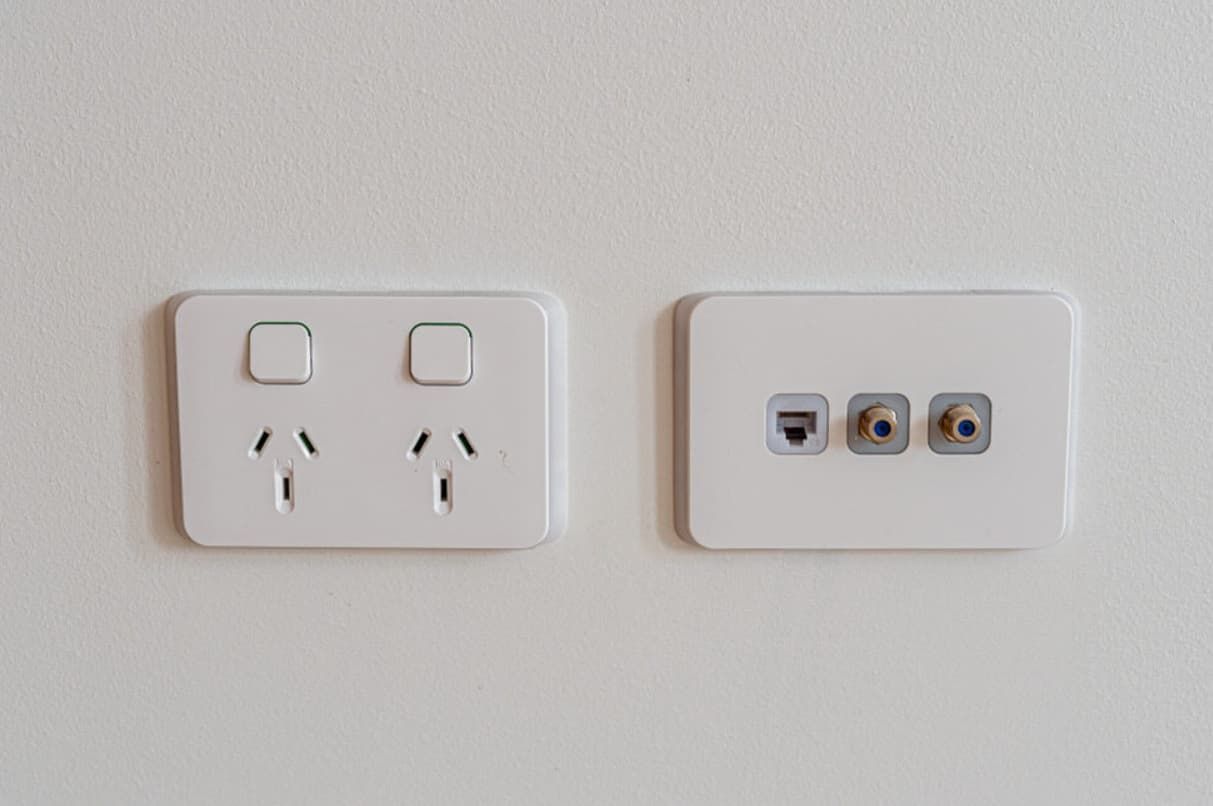 Two White Electrical Outlets And A Light Switch On A White Wall — Mozzlec Electrical In Urangan, QLD