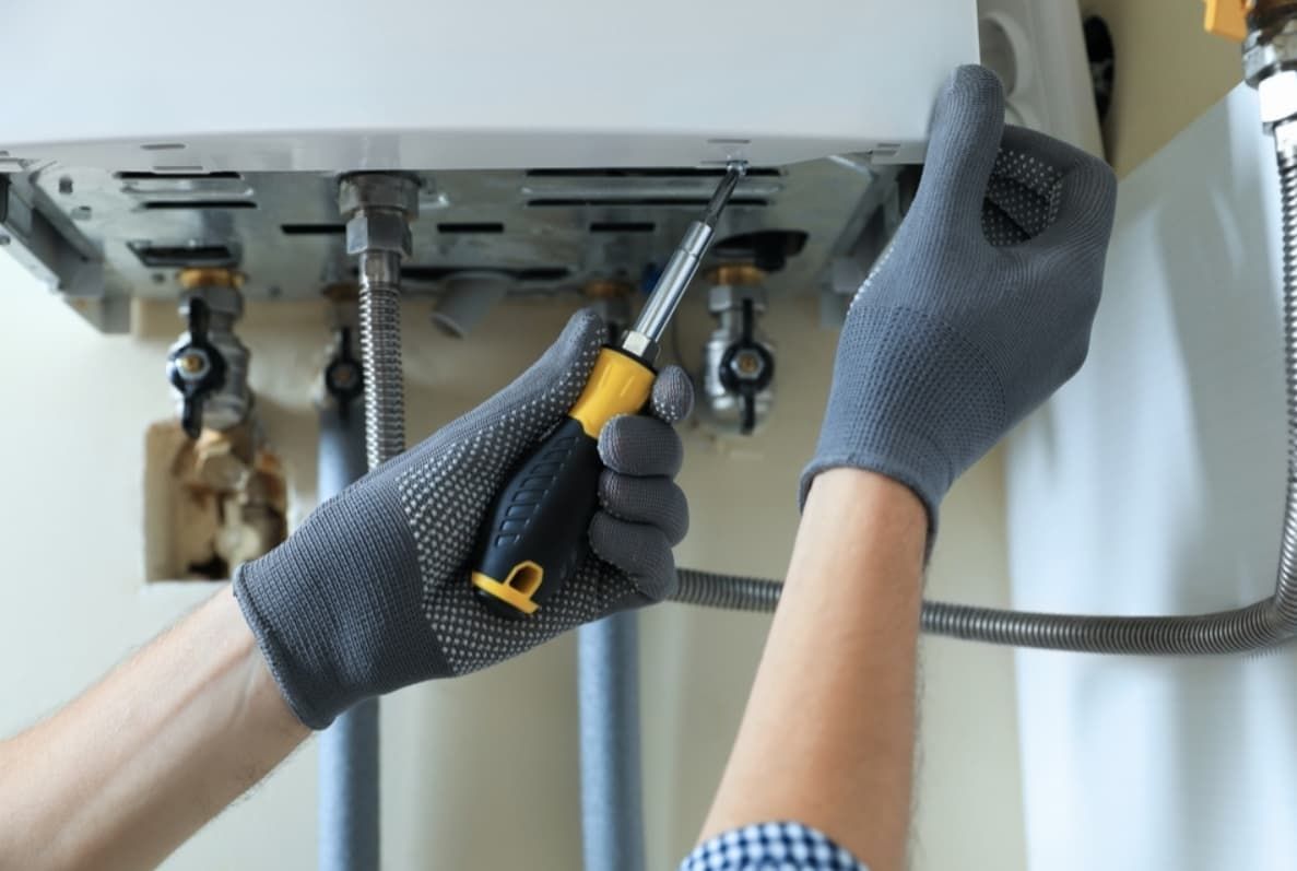 A Person Is Fixing A Water Heater With A Screwdriver — Mozzlec Electrical In Urangan, QLD