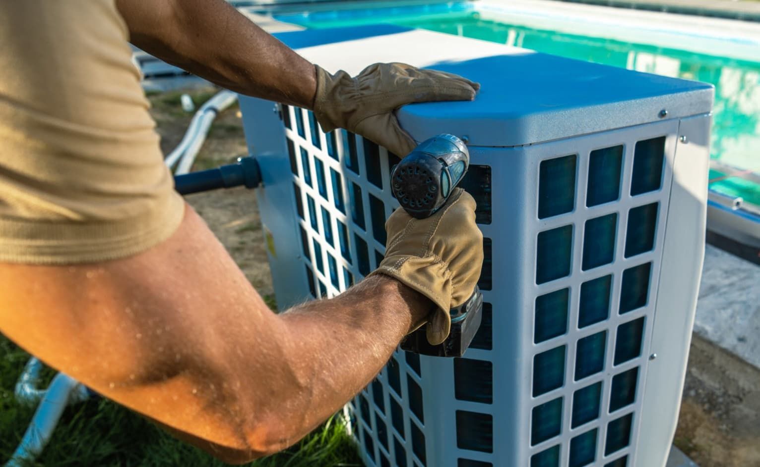 A Man Is Using A Drill To Fix An Air Conditioner Next To A Pool — Mozzlec Electrical In Urangan, QLD