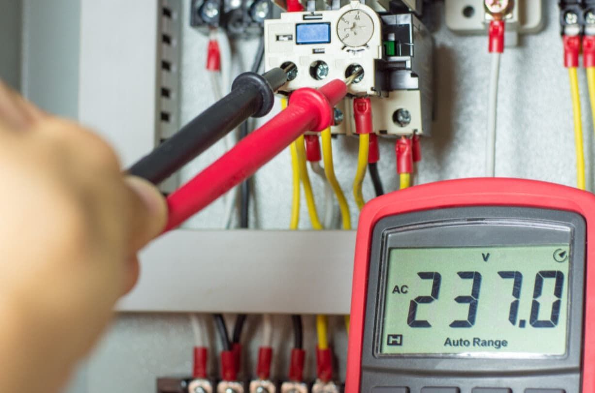 A Person Is Using A Multimeter To Measure Voltage In An Electrical Box — Mozzlec Electrical In Urangan, QLD