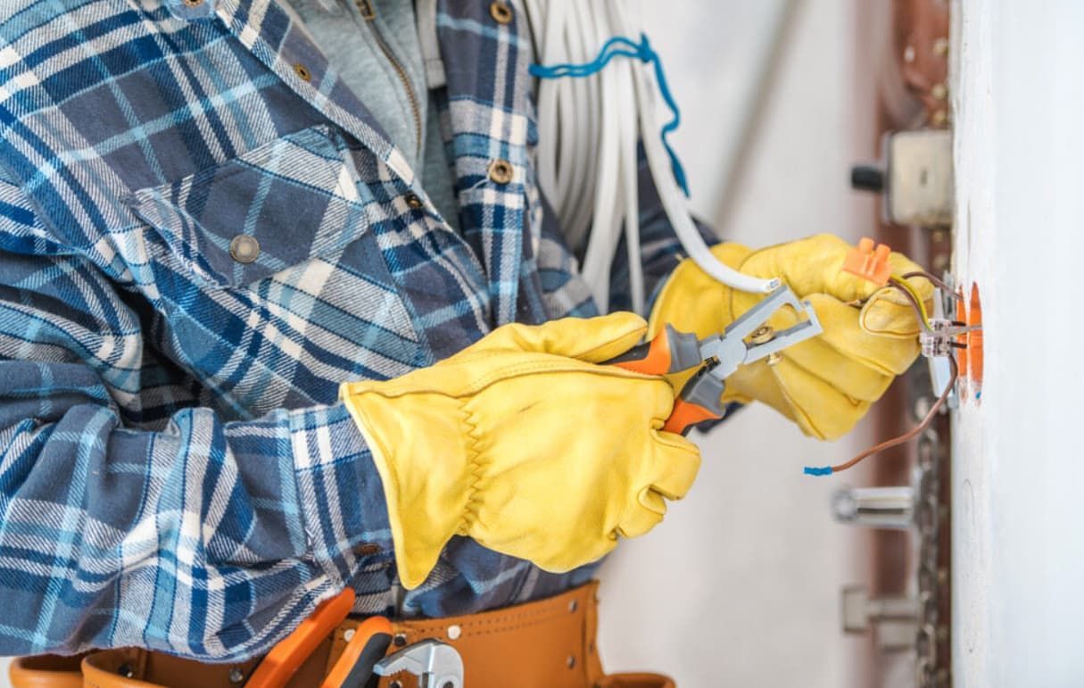 An Electrician Is Working On A Wall With A Pair Of Pliers — Mozzlec Electrical In Urangan, QLD