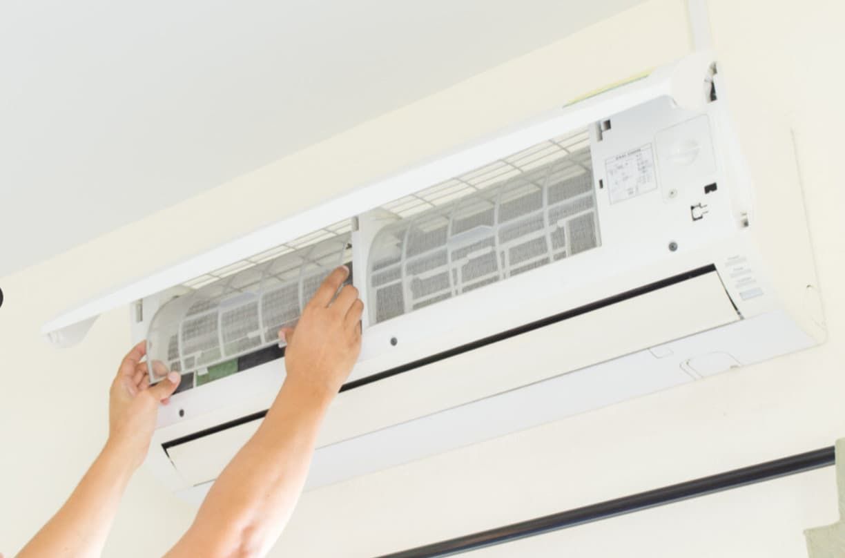 A Person Is Cleaning A Wall Mounted Air Conditioner — Mozzlec Electrical In Urangan, QLD