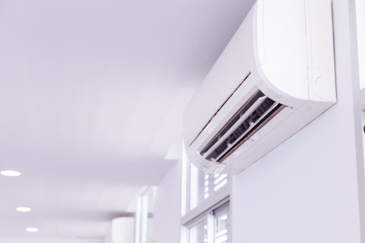 A White Air Conditioner Is Hanging On A White Wall In A Hallway — Mozzlec Electrical In Urangan, QLD