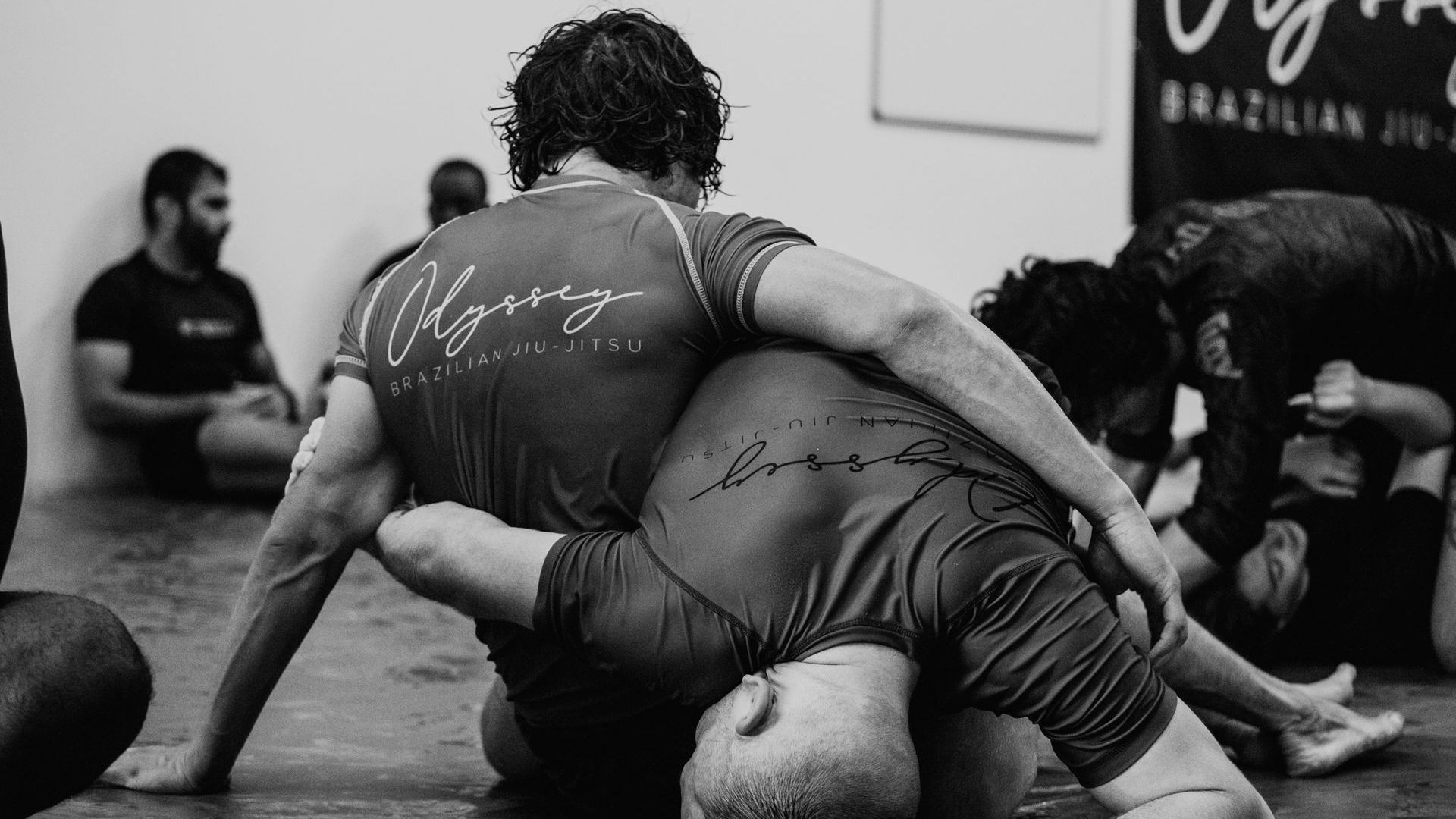 two men are wrestling on a mat in a gym .