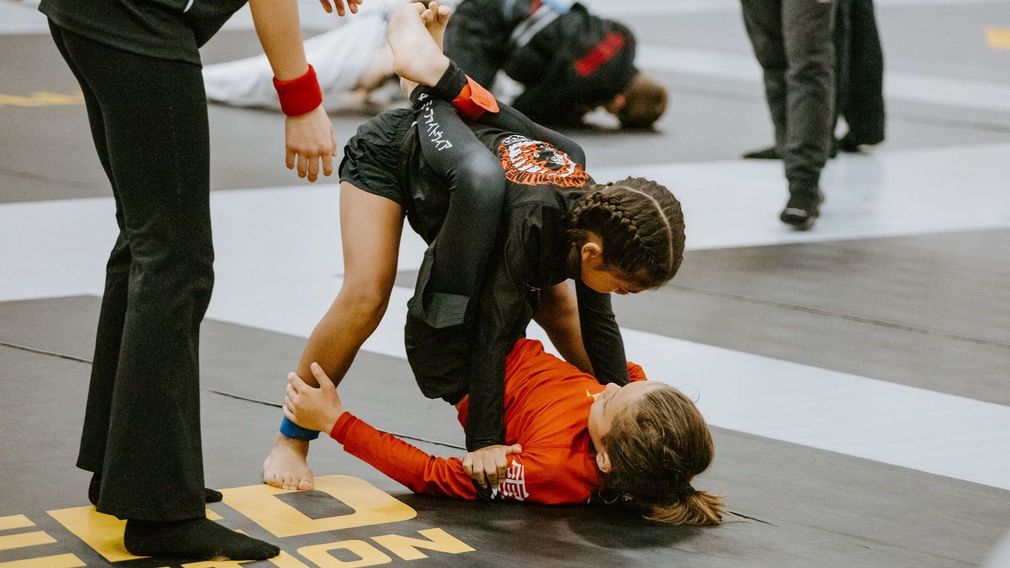 a man and a little girl are practicing jiu jitsu on a mat .