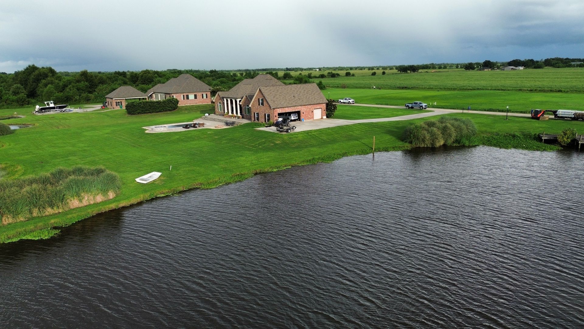 An aerial view of a house in the middle of a field next to a lake.