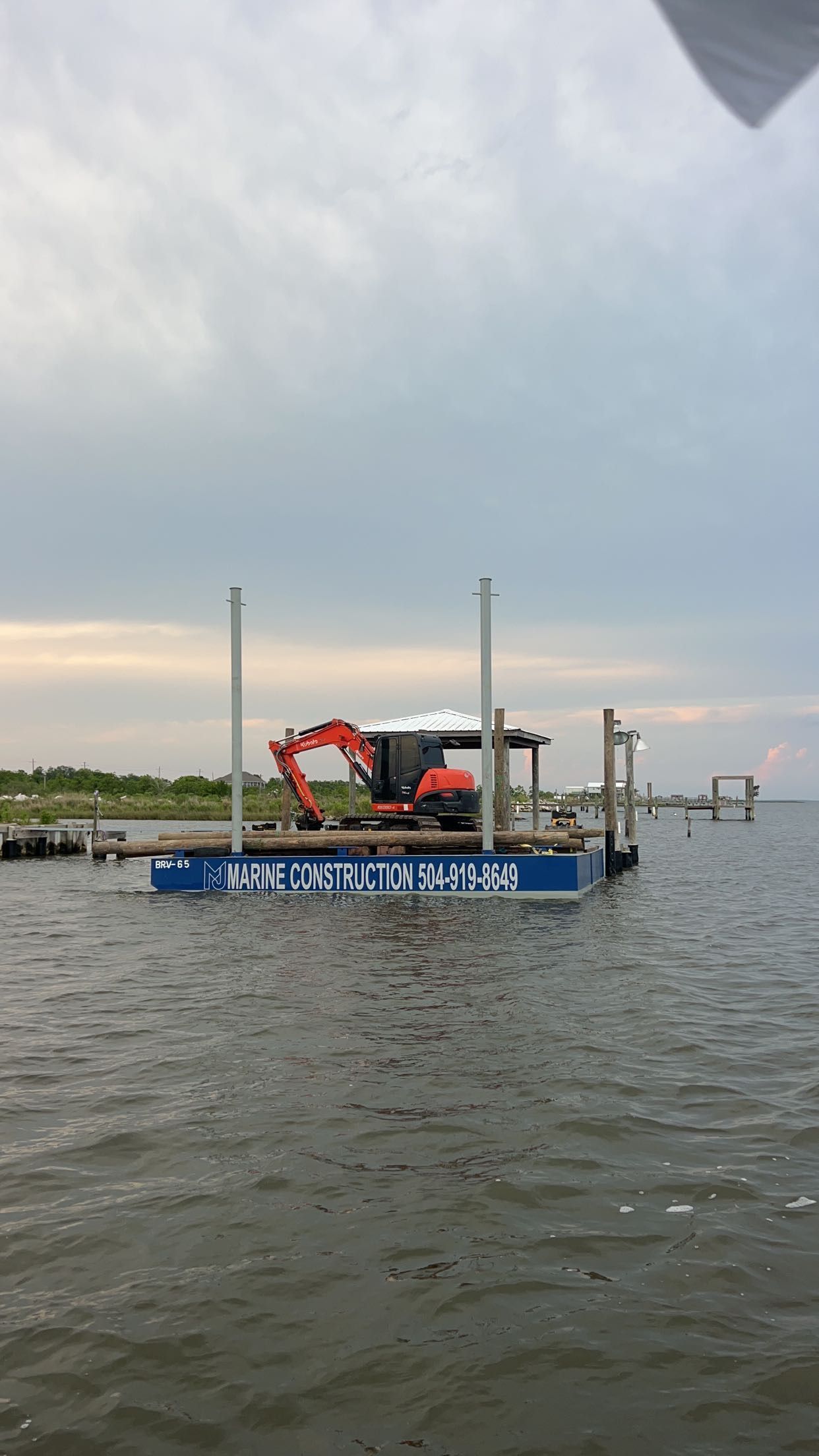 An excavator is on a floating platform in the water