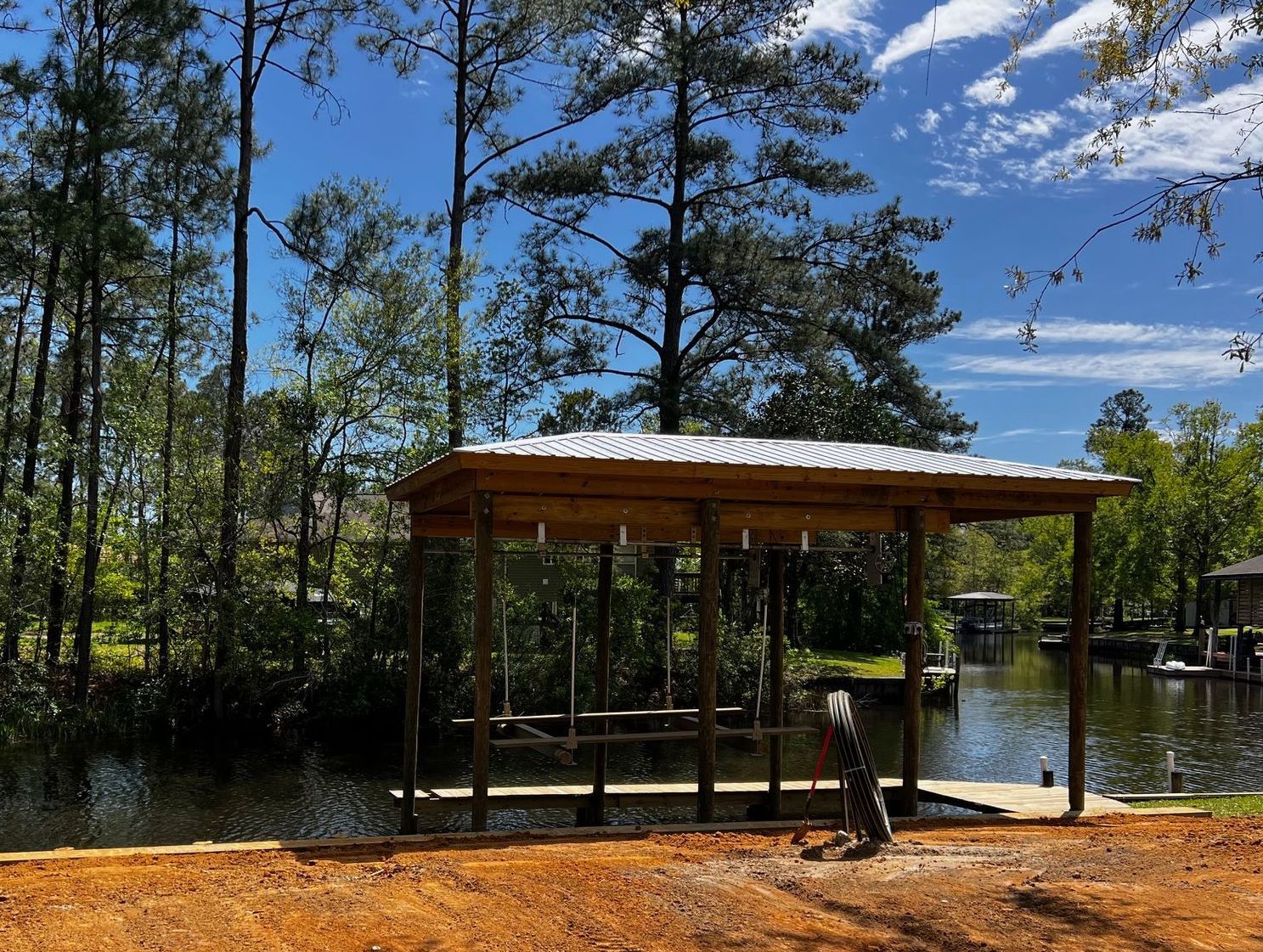 A wooden pavilion is sitting next to a body of water surrounded by trees.