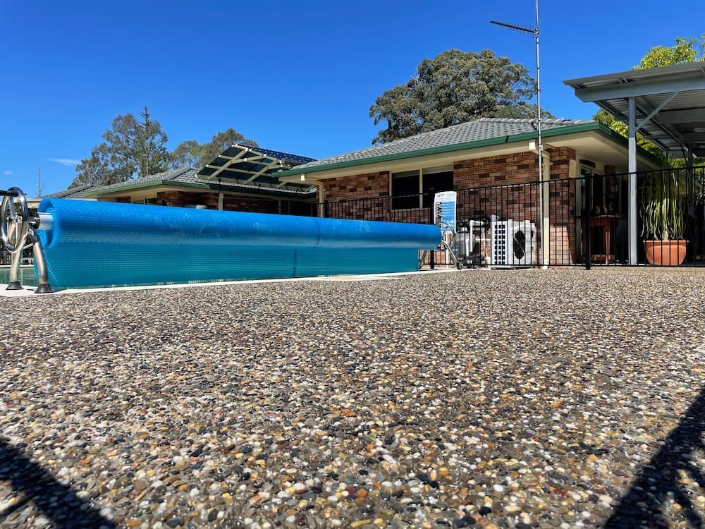 A Large Swimming Pool Is Sitting In Front Of A House — Brodie Wynter Concreting in Port Macquarie, NSW