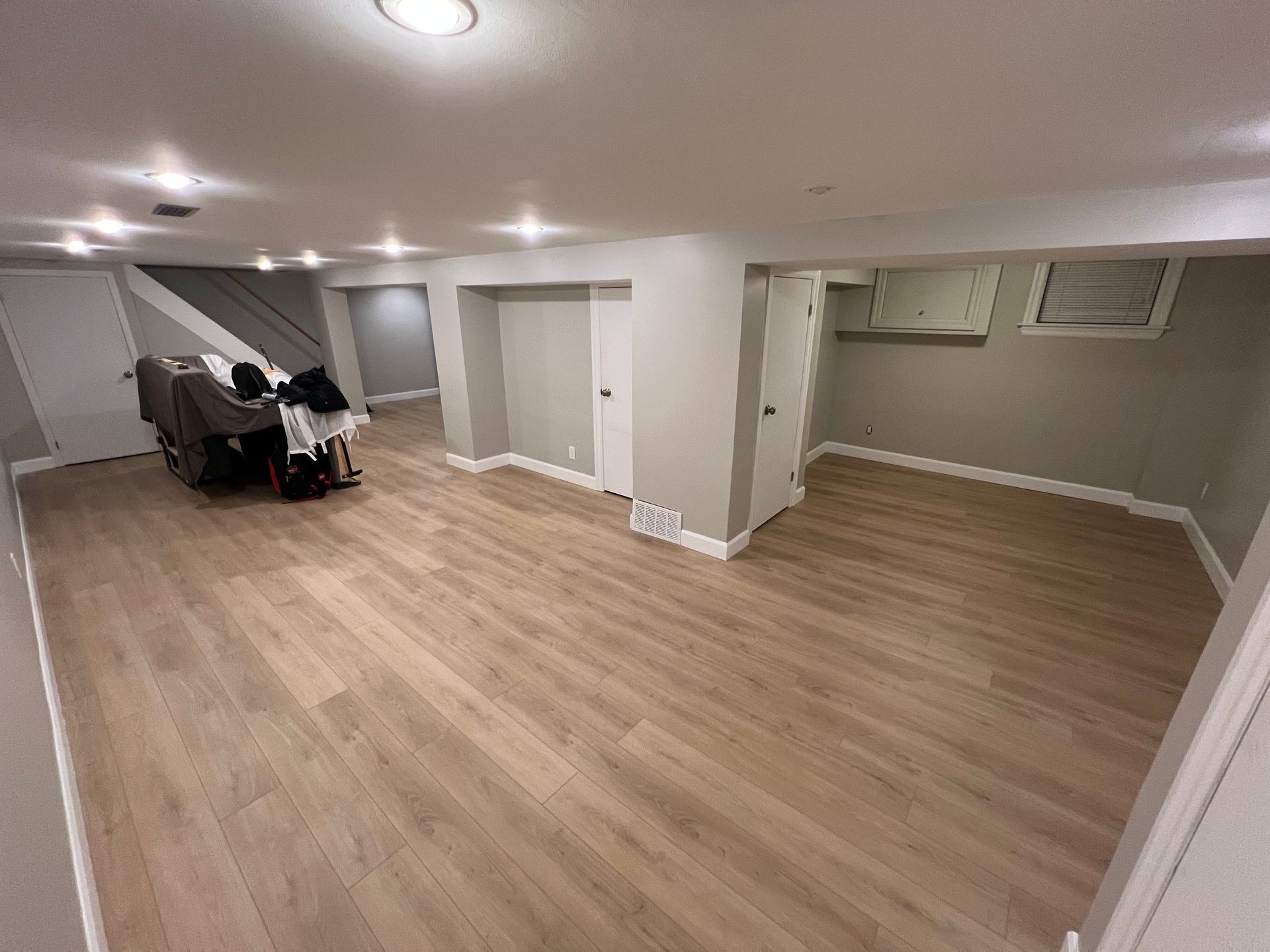 An empty basement with hardwood floors and stairs.
