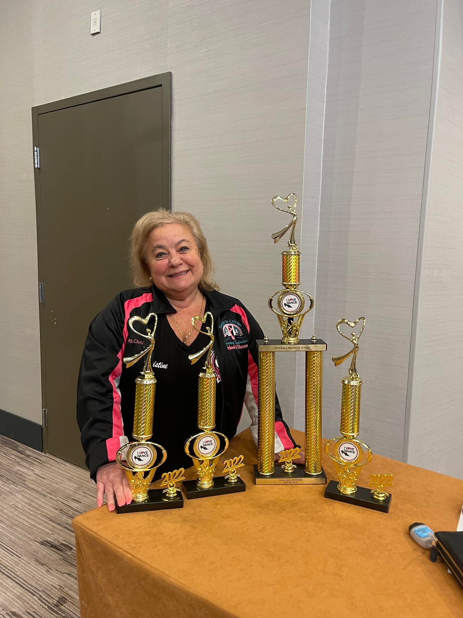A woman is standing next to a table with trophies on it.