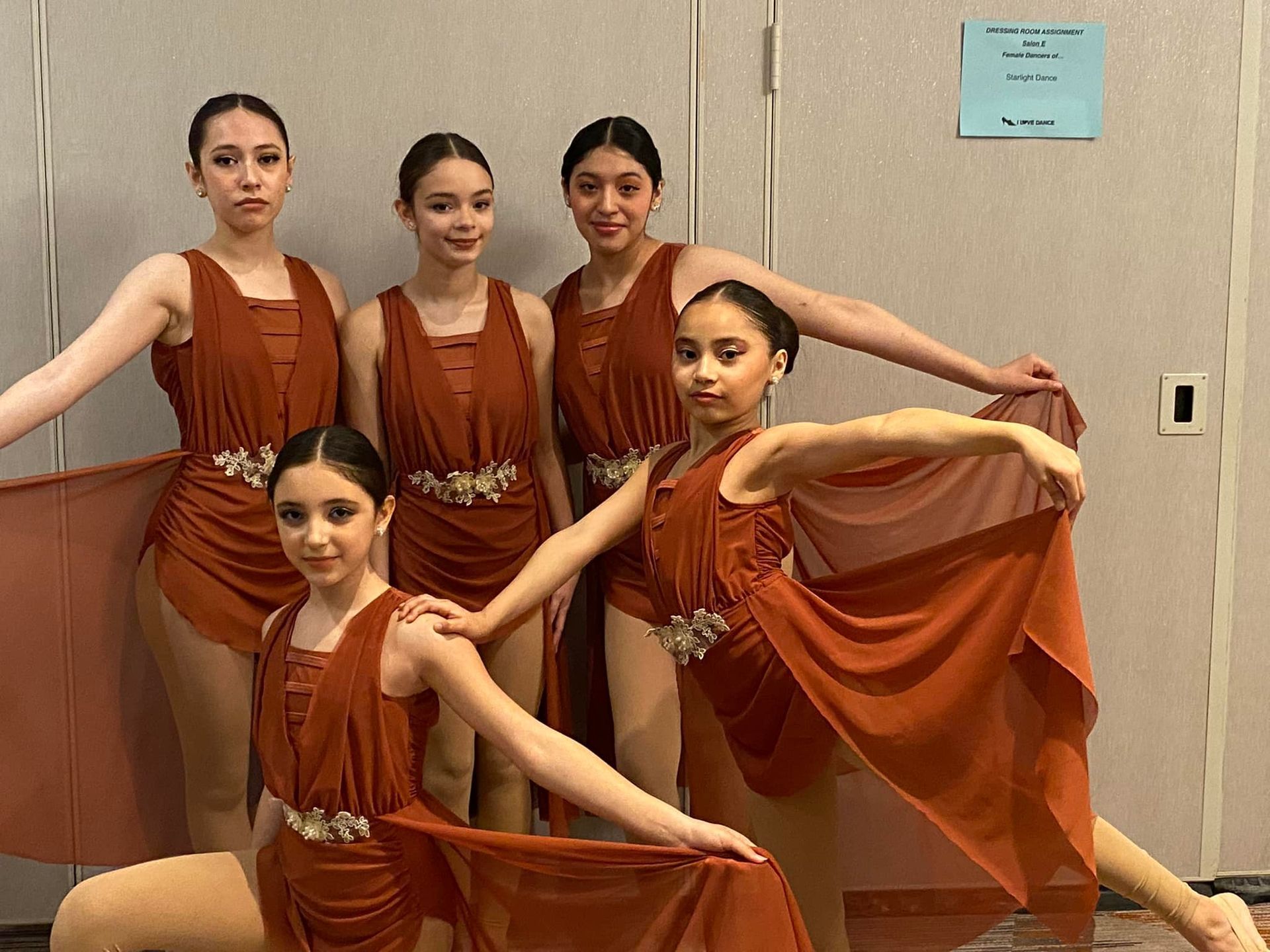 A group of young girls are posing for a picture in front of a door.
