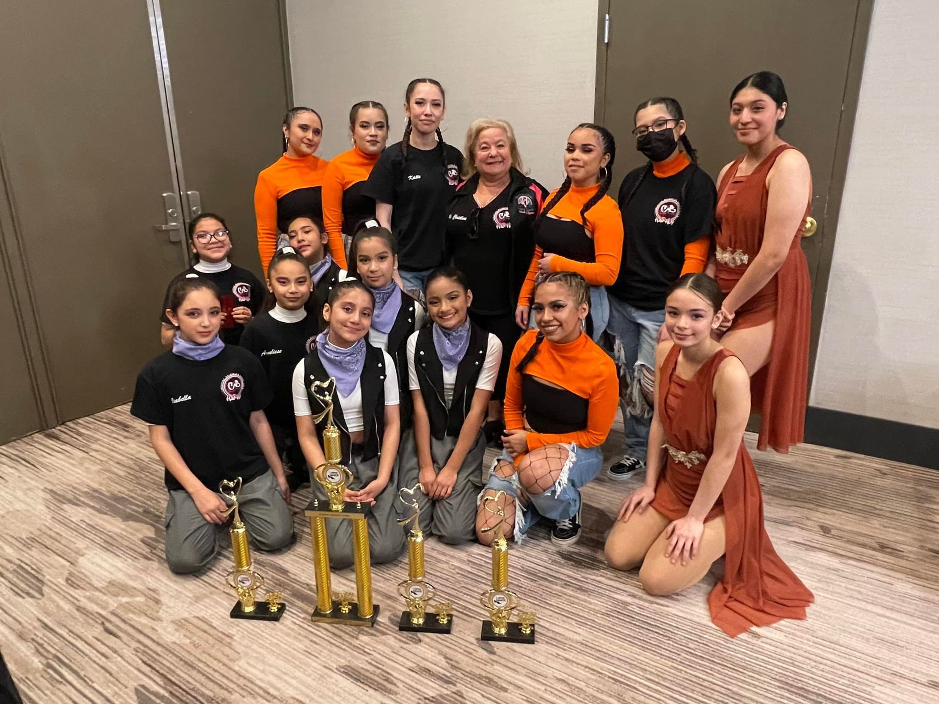 A group of young girls are posing for a picture with trophies.