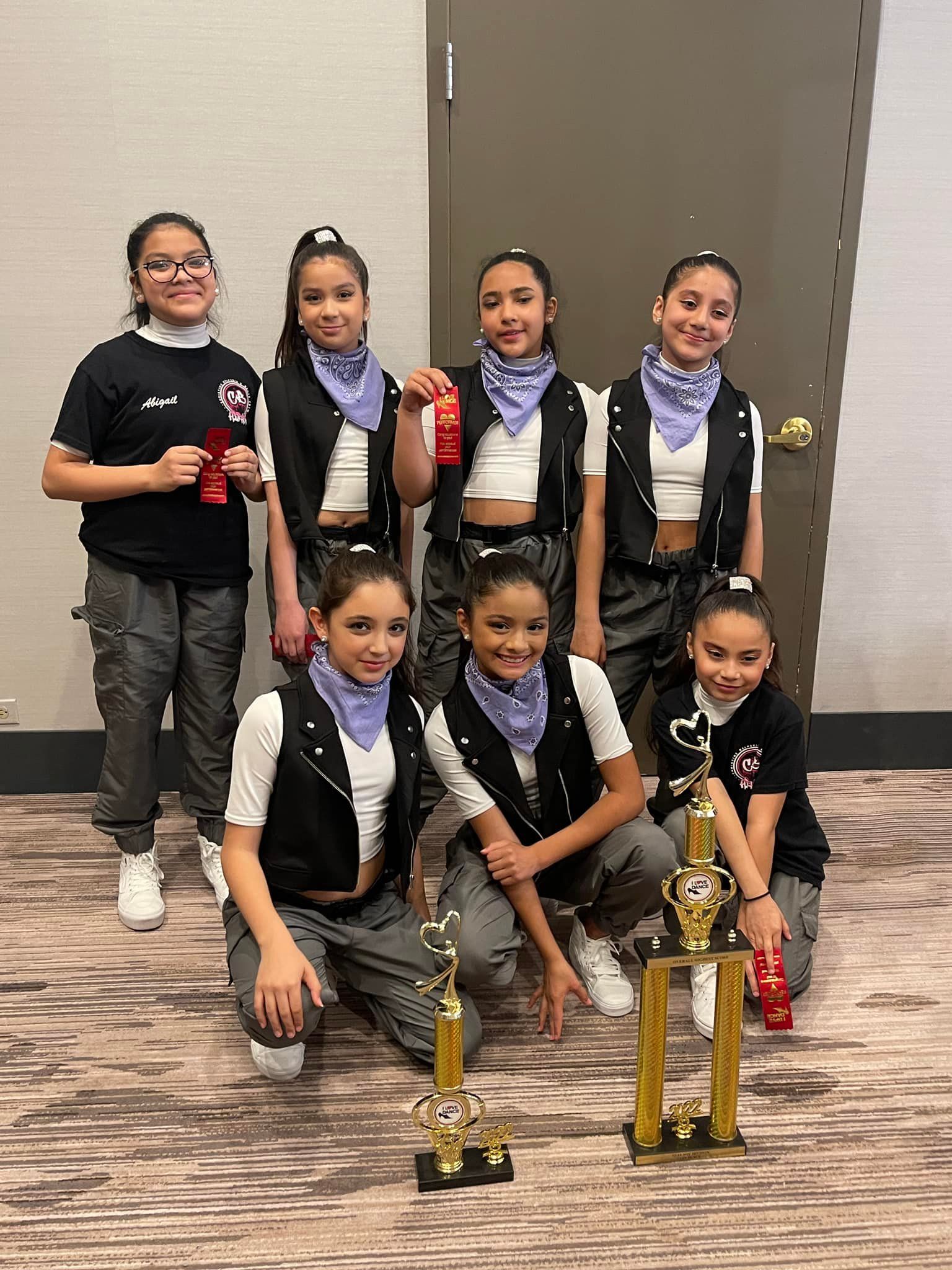 A group of young girls are posing for a picture with trophies.