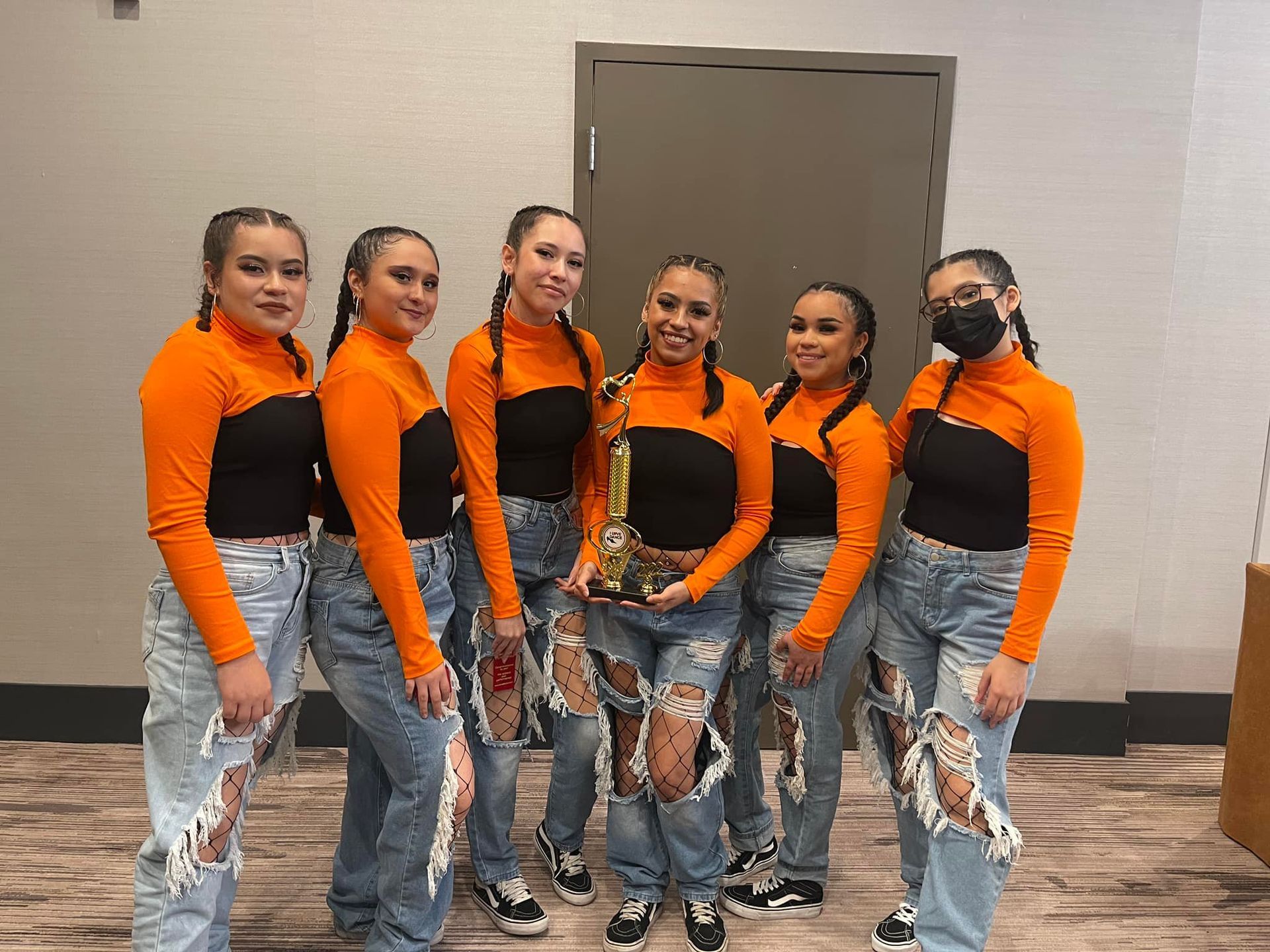 A group of young women are standing next to each other holding a trophy.