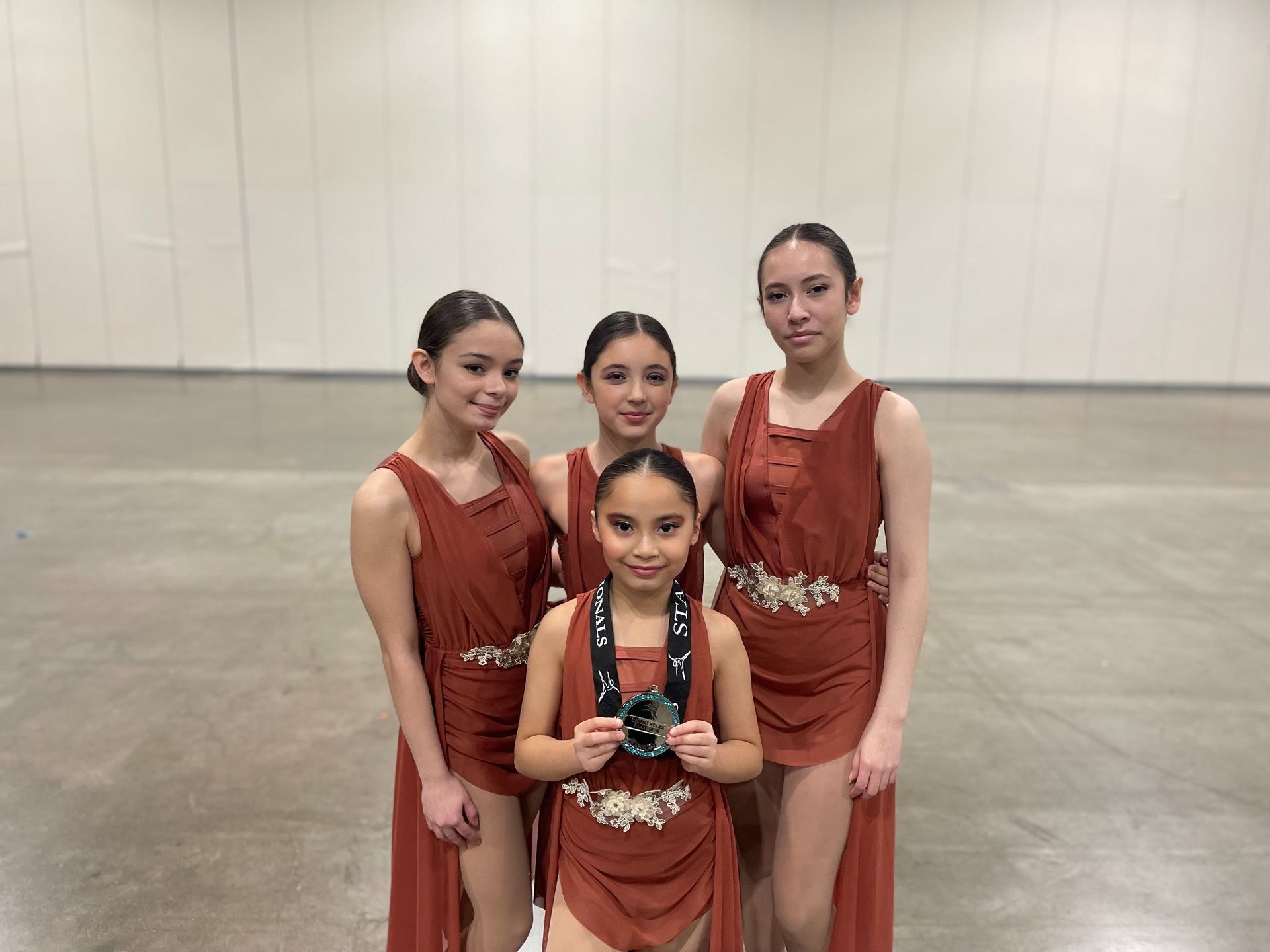 A group of young girls are standing next to each other in a room holding medals.