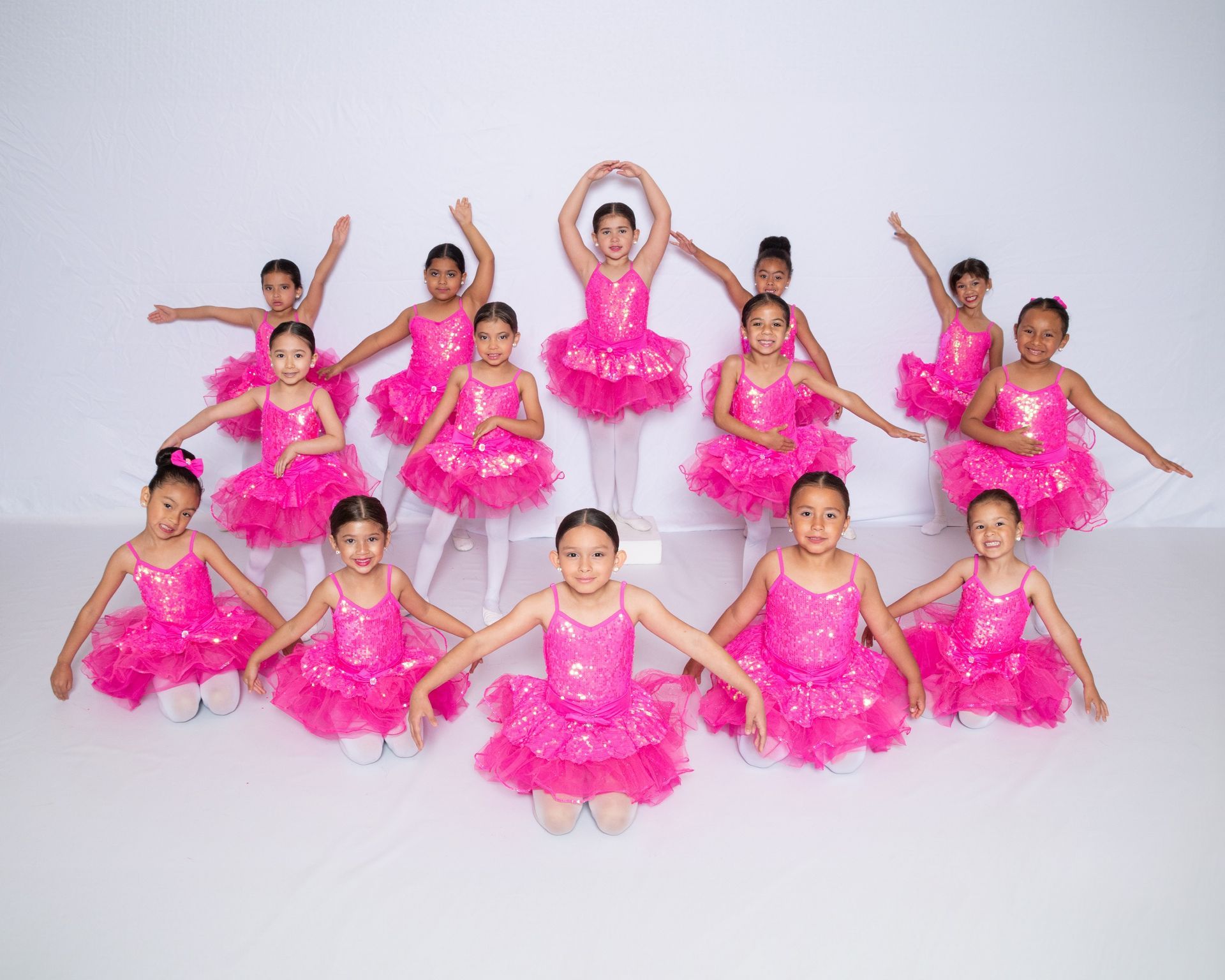 A group of young girls in pink tutus are posing for a picture.