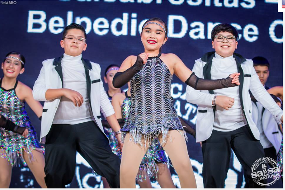 A group of young people are dancing in front of a sign that says belvedere dance