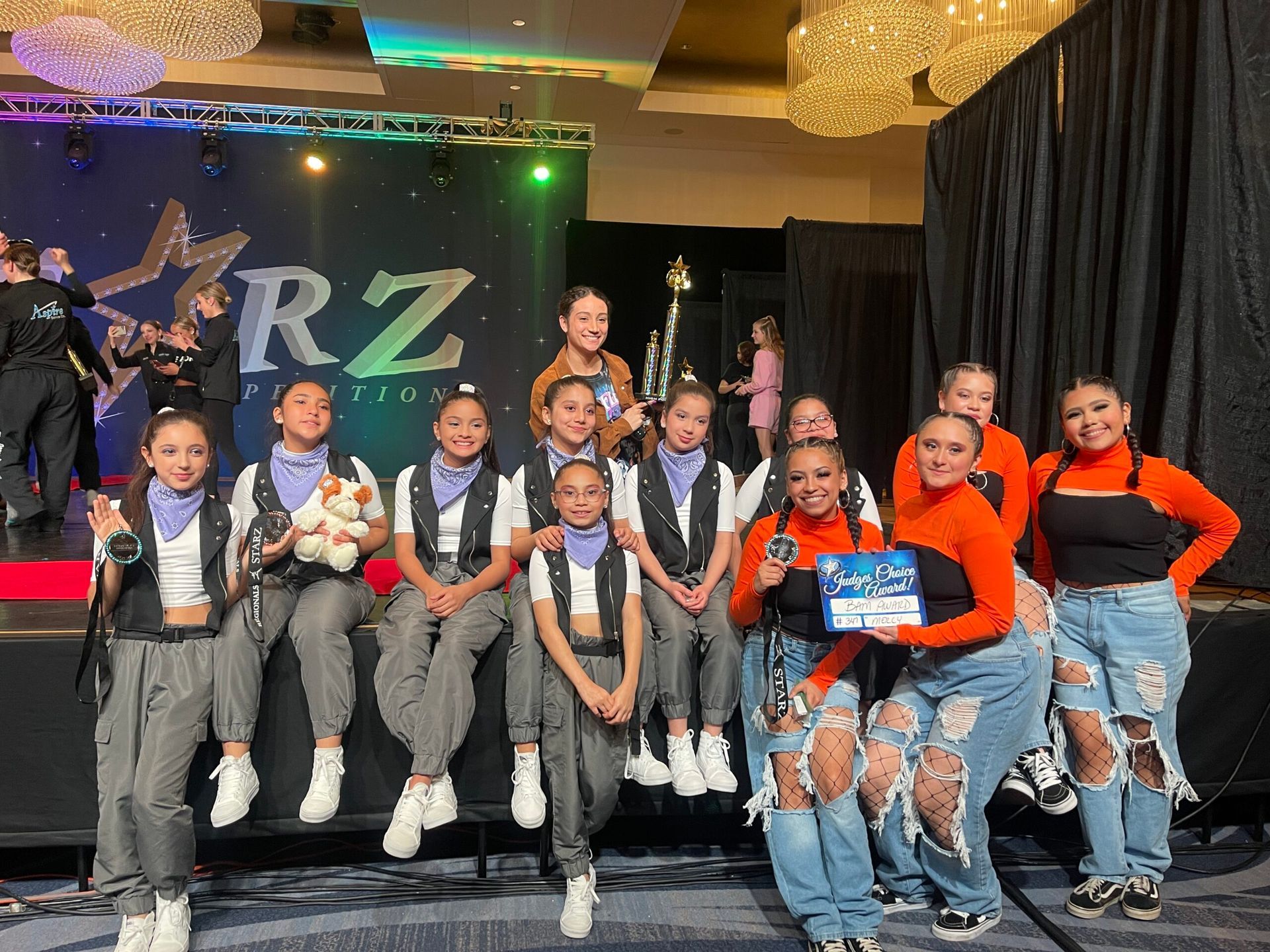 A group of young girls are posing for a picture on a stage.