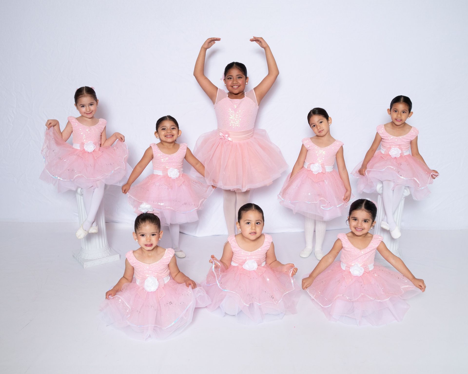 A group of young ballerinas in pink tutus are posing for a picture.